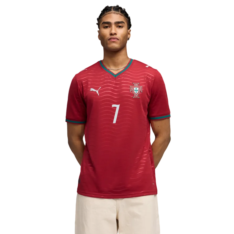 A man wearing a red Morocco national team soccer jersey with the number 7, standing against a black background.