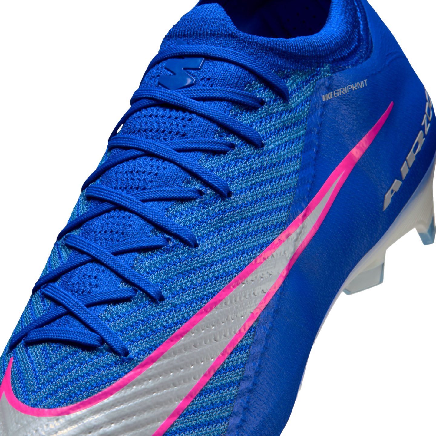 Close-up of a blue Nike soccer cleat featuring a vibrant pink and silver swoosh, blue laces, and a textured knit upper against a black background.