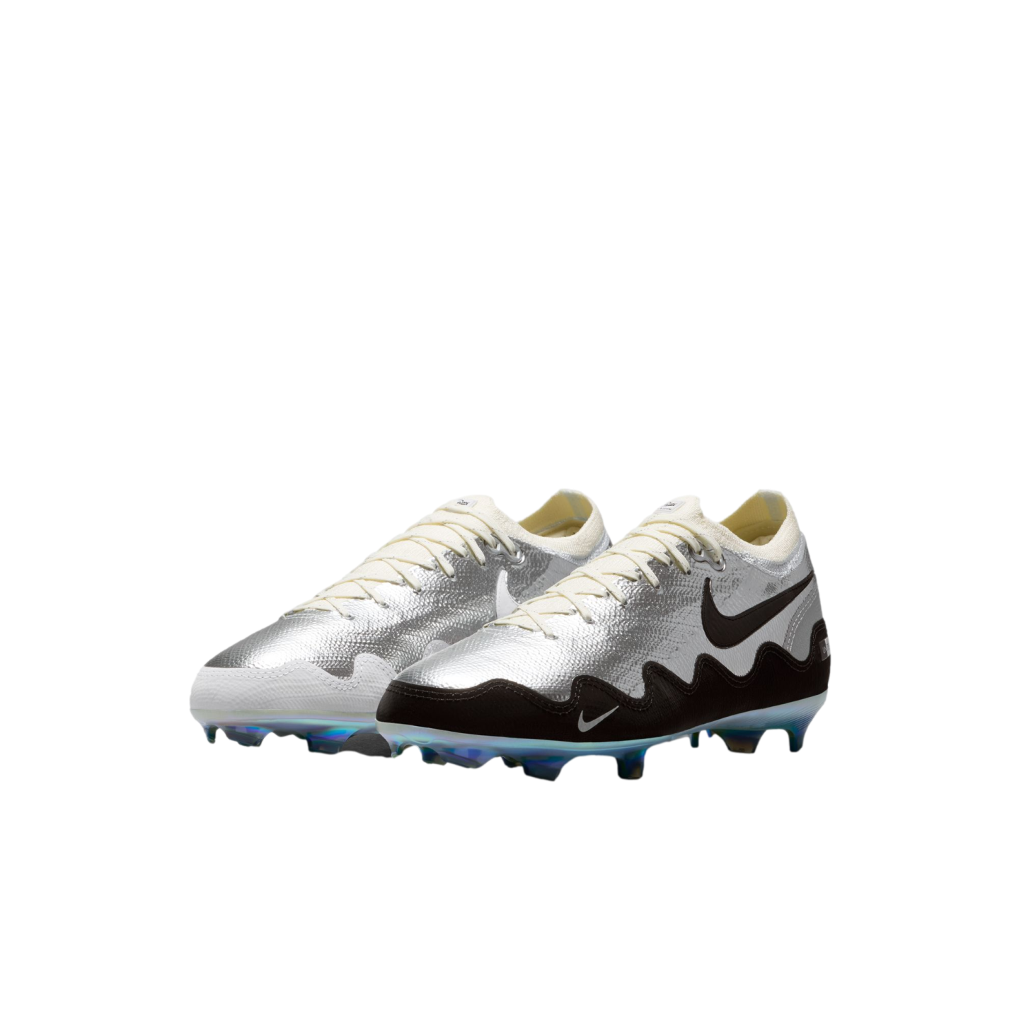 A pair of silver Nike soccer cleats with a wavy black pattern on the side of one shoe and a white one on the other, off-white laces, and iridescent blue-tinted studs, positioned against a solid black background.