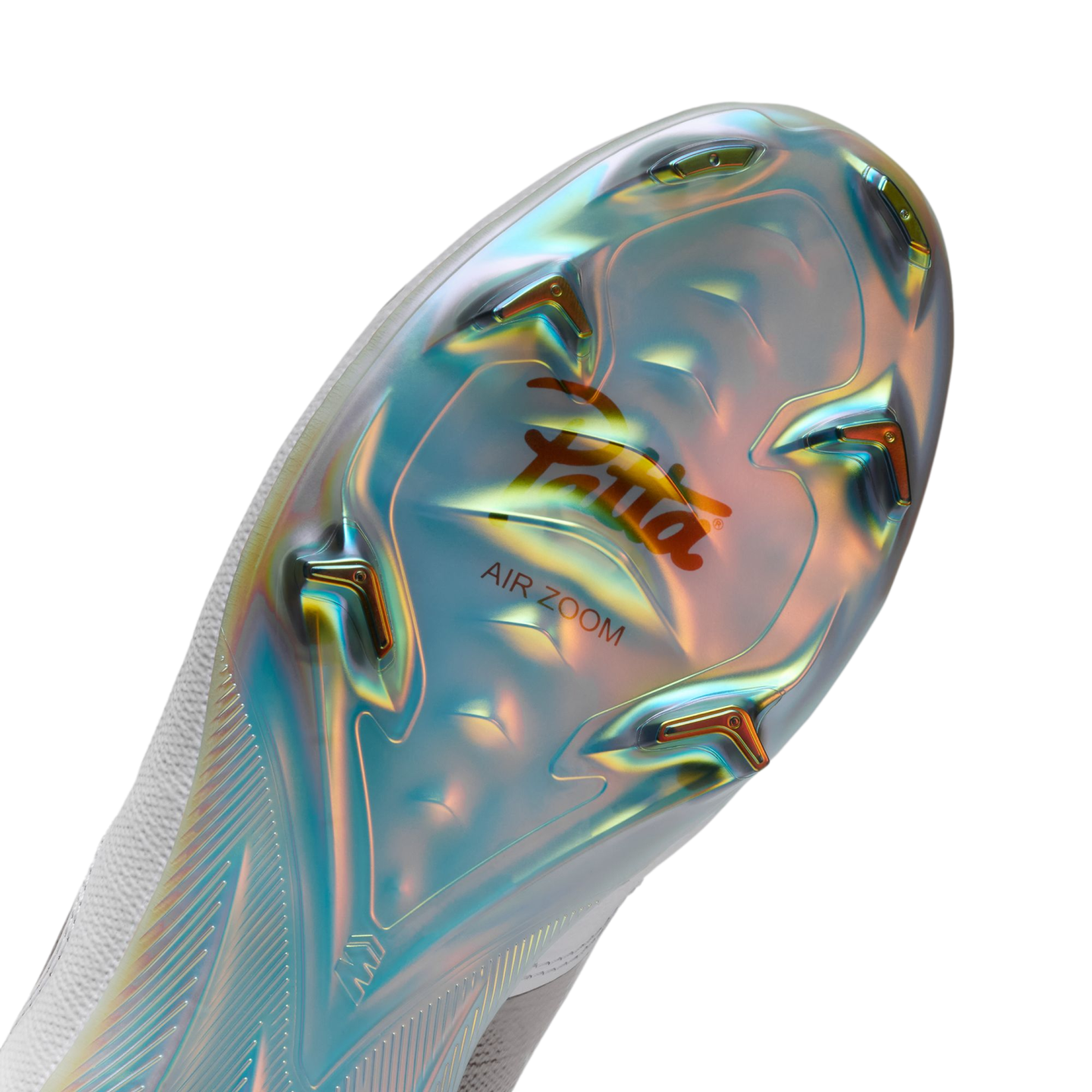 A close-up view of the iridescent soleplate of a Nike x Patta soccer cleat. The plate features a shimmering, multi-colored finish in blue and gold, with several angular studs and an orange "Patta" script logo above the words "AIR ZOOM."