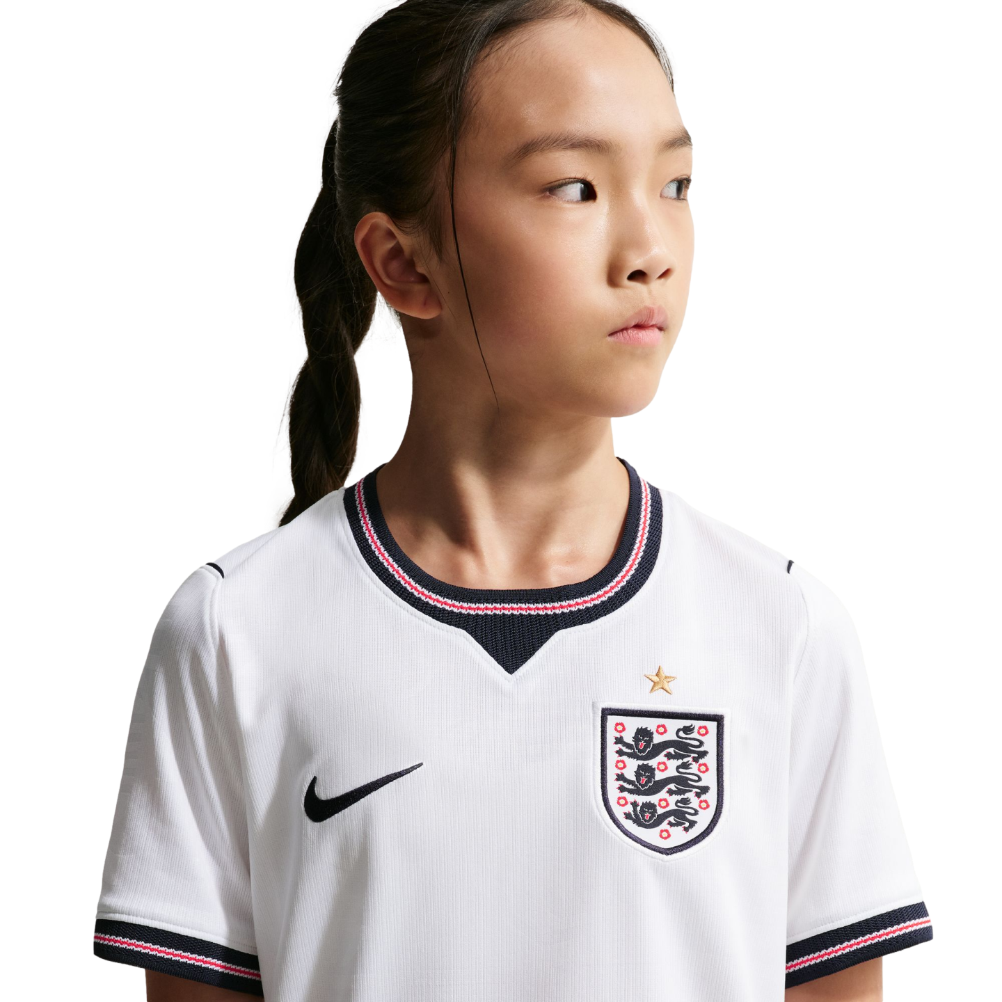 A young girl in a white England national football team jersey looking to the side against a black background.