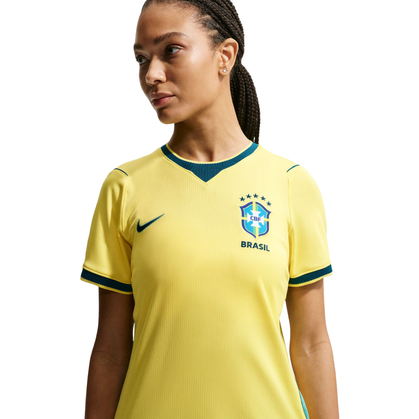 A woman with braided hair wearing a yellow Brazil soccer jersey, looking away against a black background.