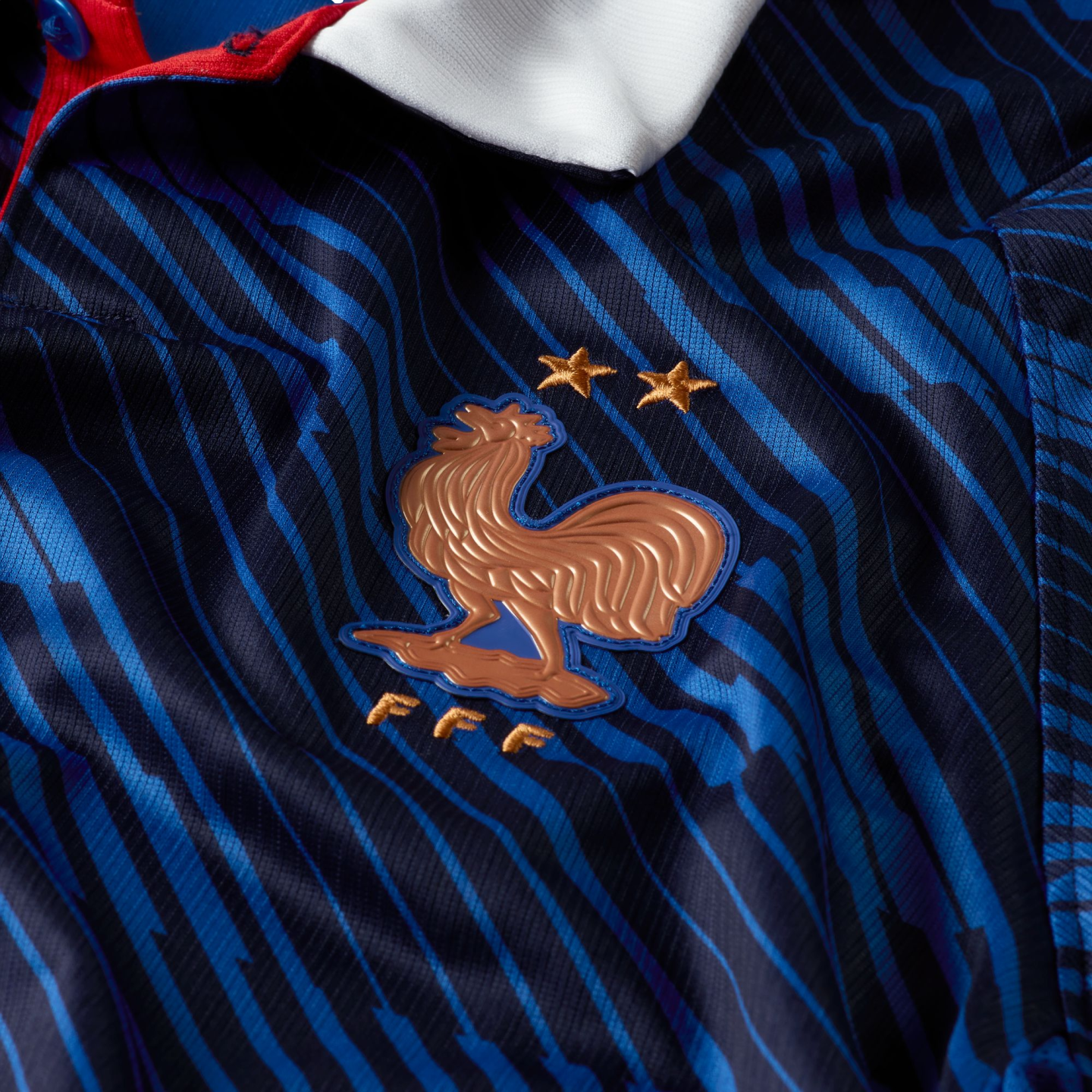 Close-up of a blue striped France soccer jersey with a gold rooster crest, two stars, and "FFF" initials.