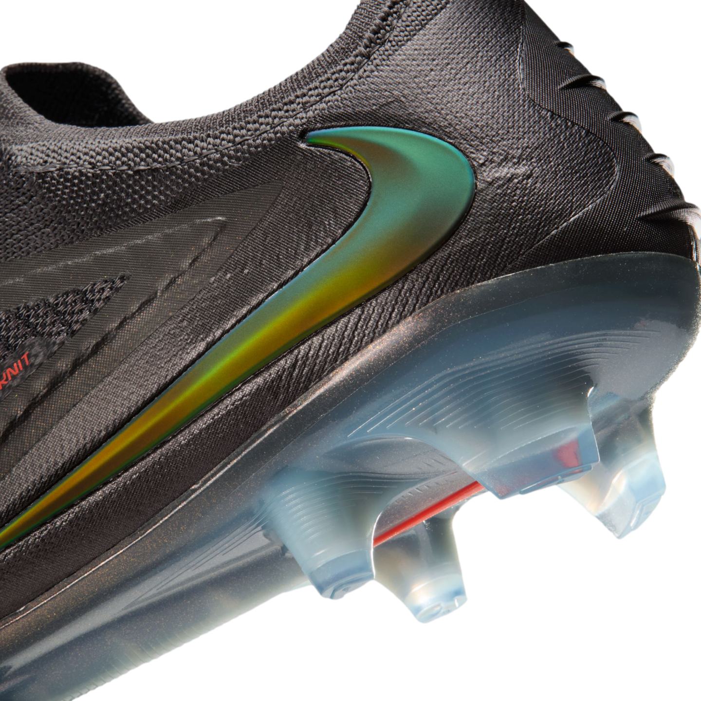 Close-up of a black Nike soccer cleat with an iridescent green swoosh, textured upper, and translucent blue sole with clear studs.