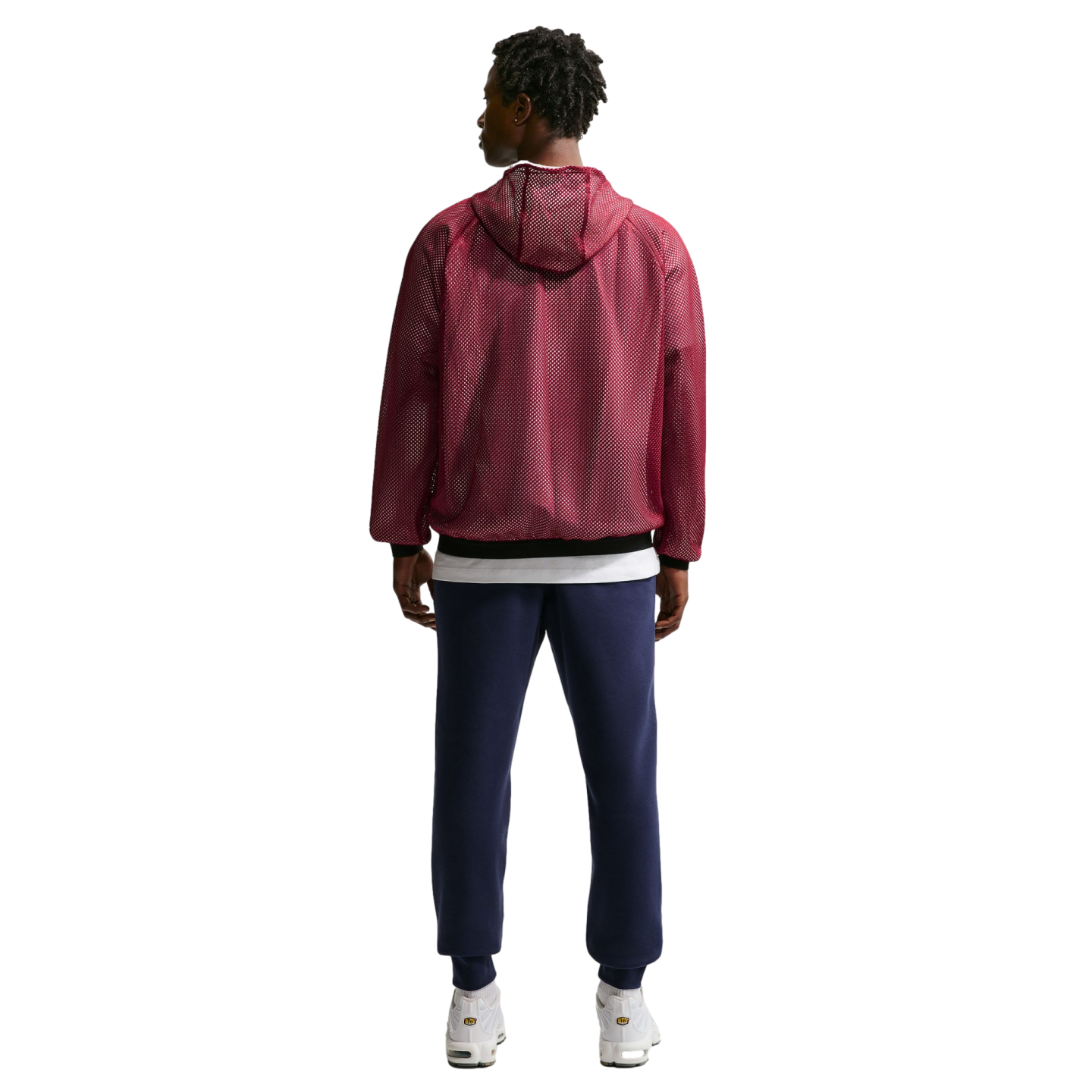 Full-body back view of a man wearing a maroon mesh hooded jacket, navy blue sweatpants, and white sneakers against a black background.