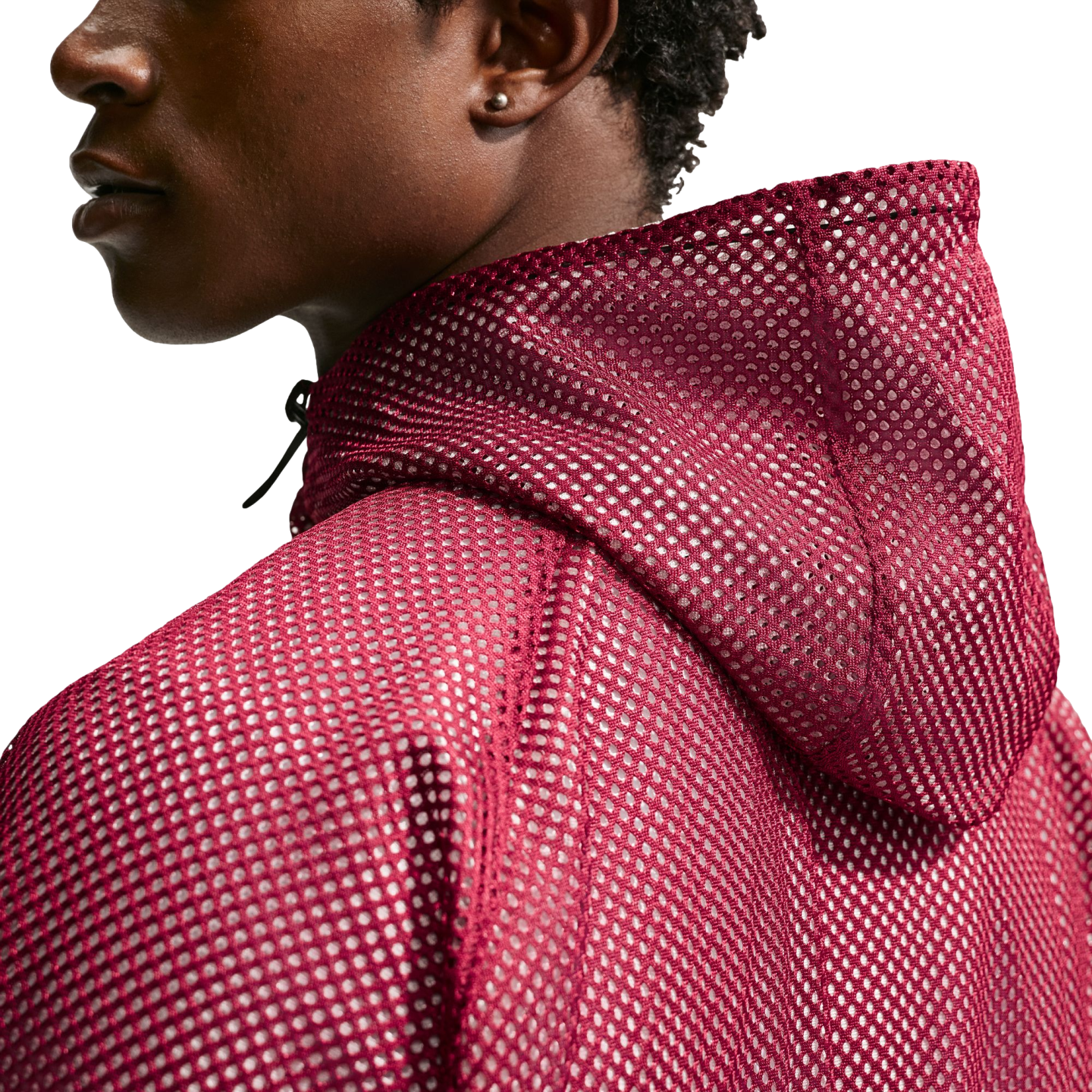 A profile view of a person wearing a burgundy mesh hoodie against a solid black background.