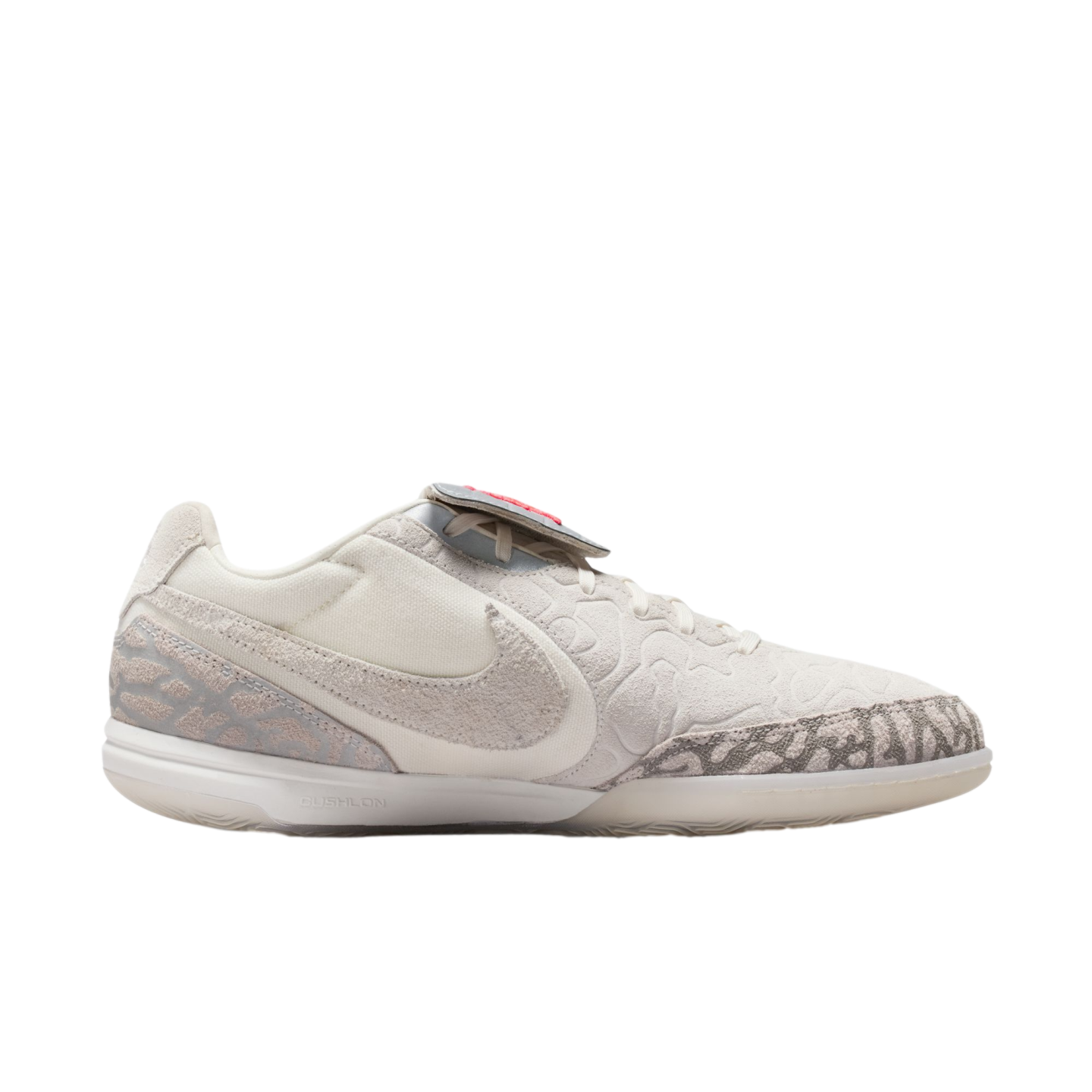 Profile view of a white Nike sneaker with light grey patterned accents on the toe and heel, a textured upper, and "CUSHLON" midsole branding, set against a black background.