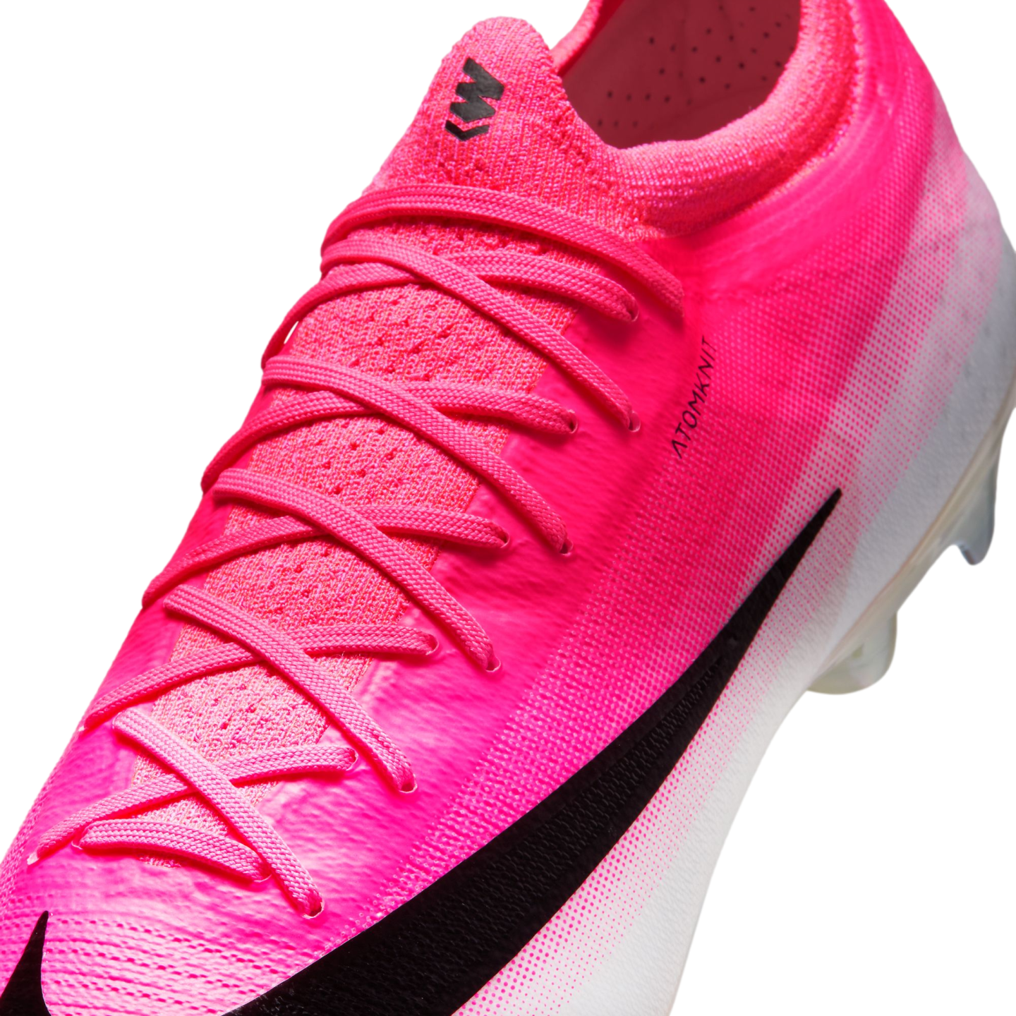 Close-up of a hot pink Nike soccer cleat featuring a black swoosh, pink laces, and the text "ATOMKNIT" on its textured upper.