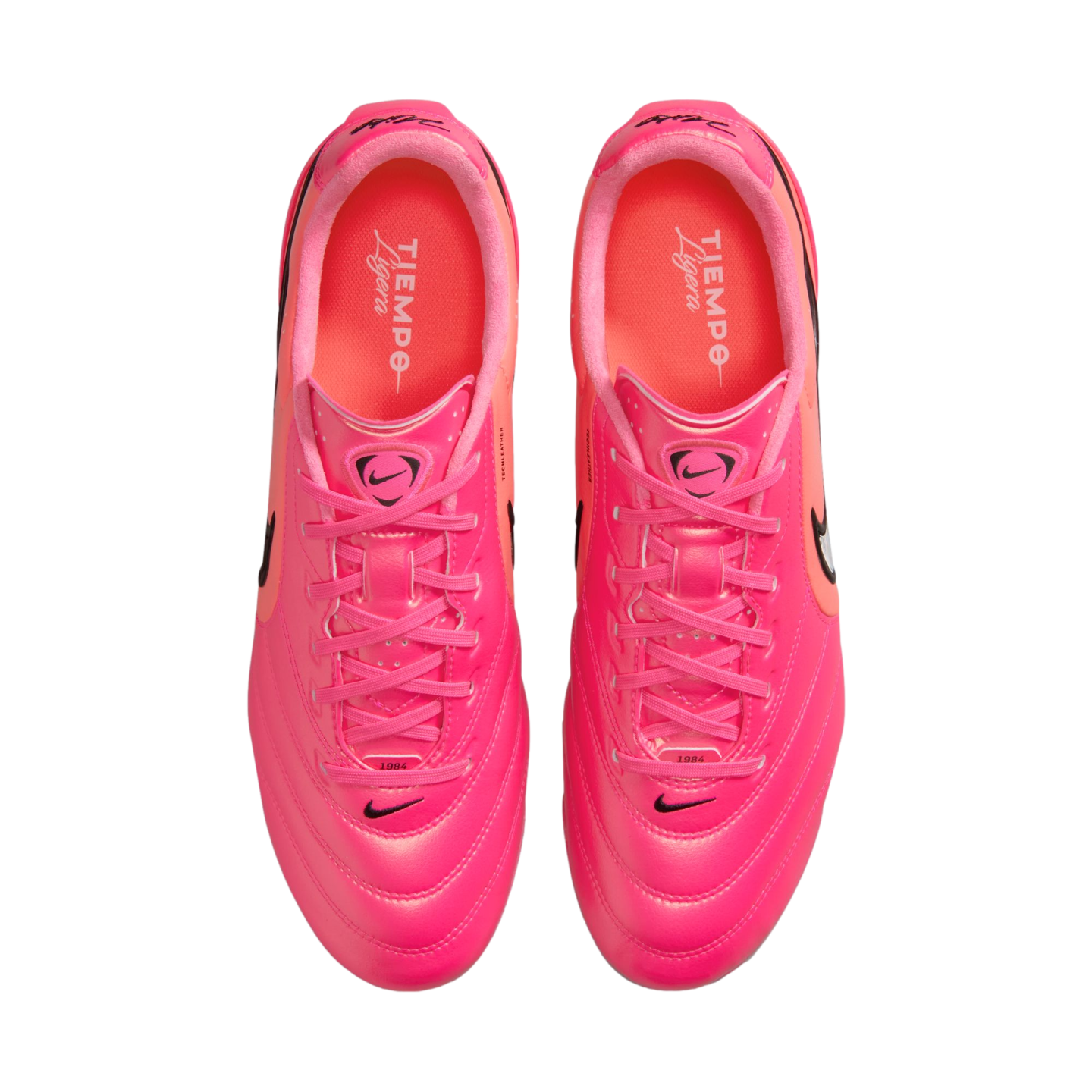 Top-down view of bright pink Nike Tiempo Ligera soccer cleats with orange-red accents and pink laces, set against a white background.