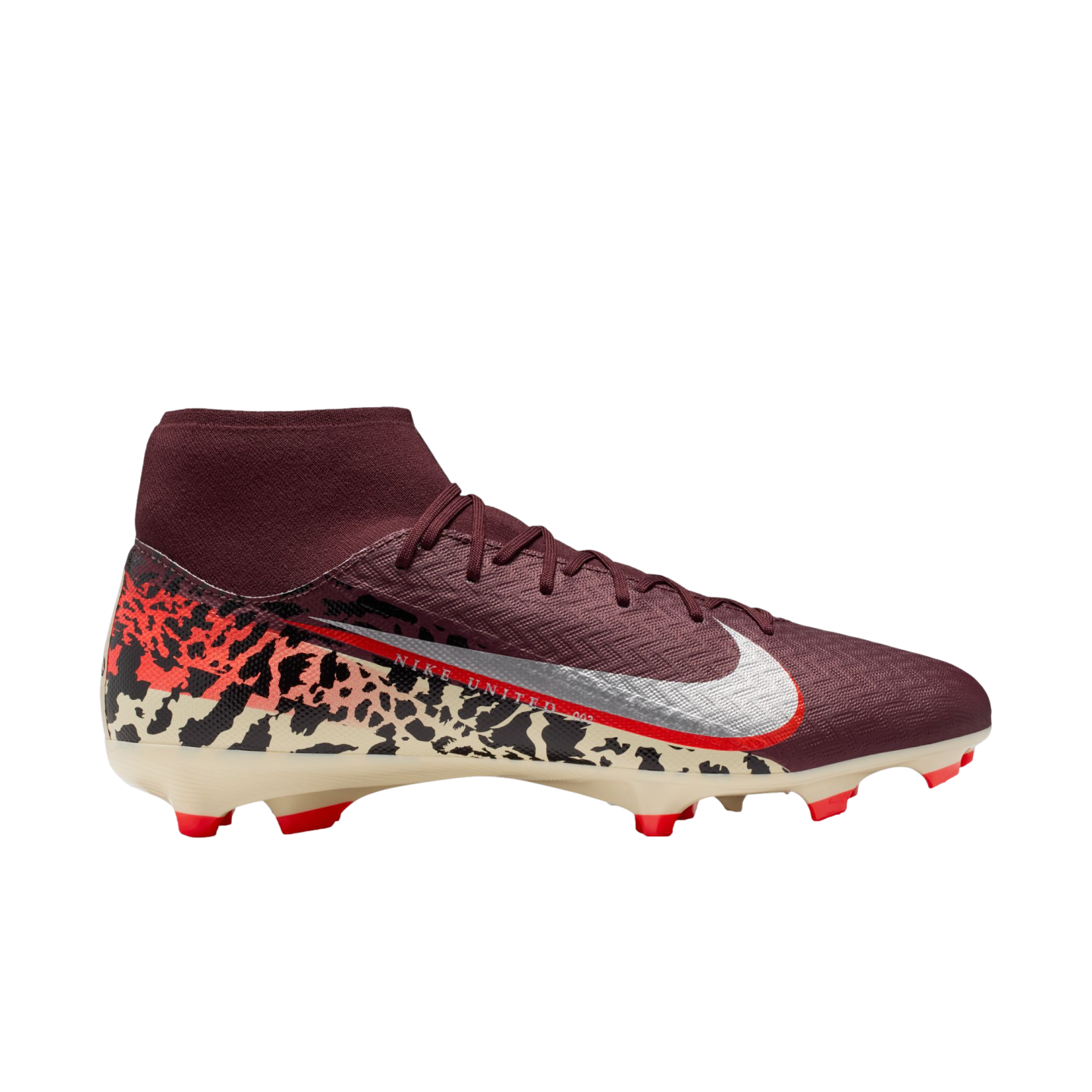 A profile view of a maroon Nike Mercurial soccer cleat against a black background. The shoe features a sock-like ankle collar, silver Swoosh with a red outline, and a cream-colored soleplate with orange studs. A bold graphic pattern in black, orange, and cream covers the heel.