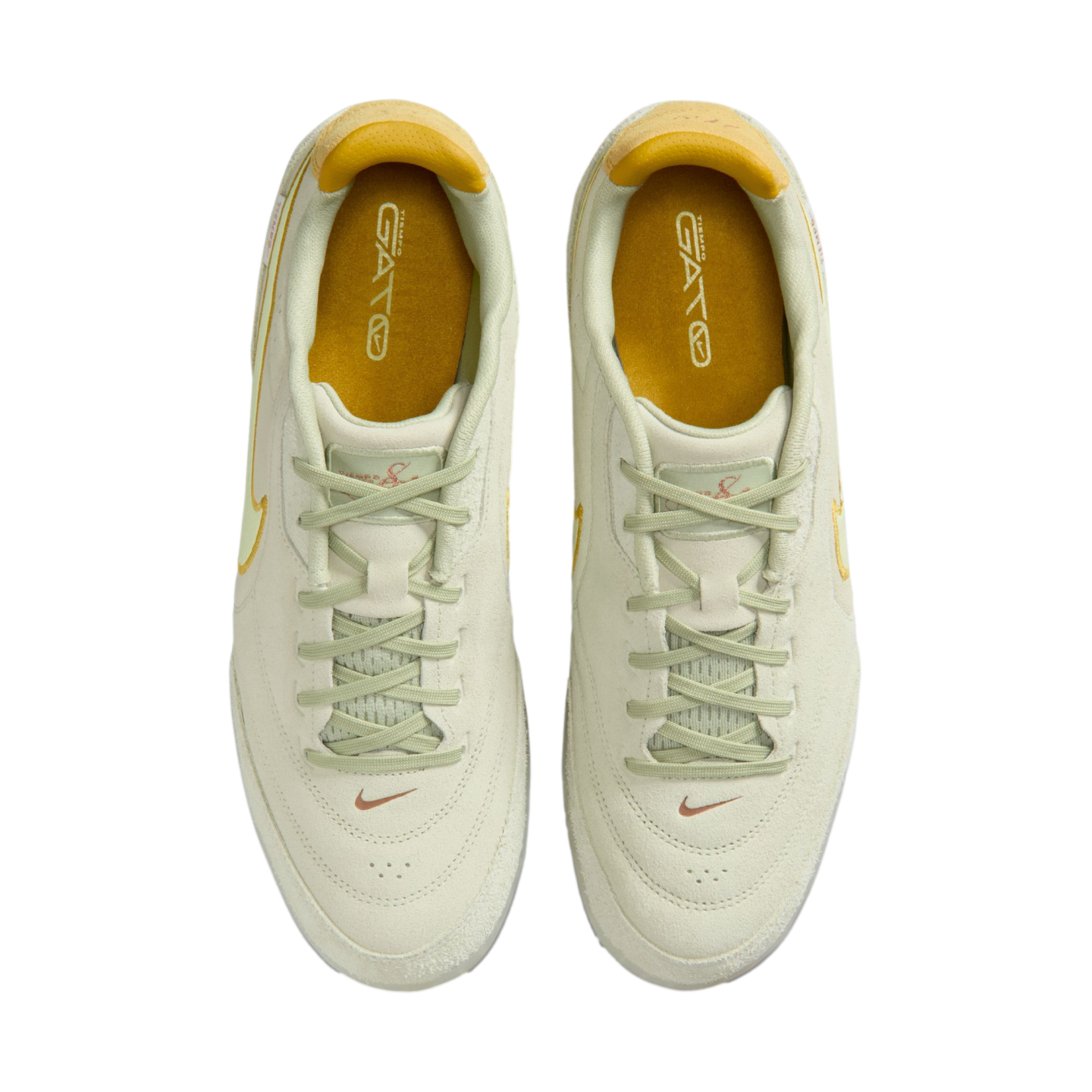 Top-down view of a pair of pale green Nike sneakers with light green laces and mustard yellow insoles, set against a solid black background.