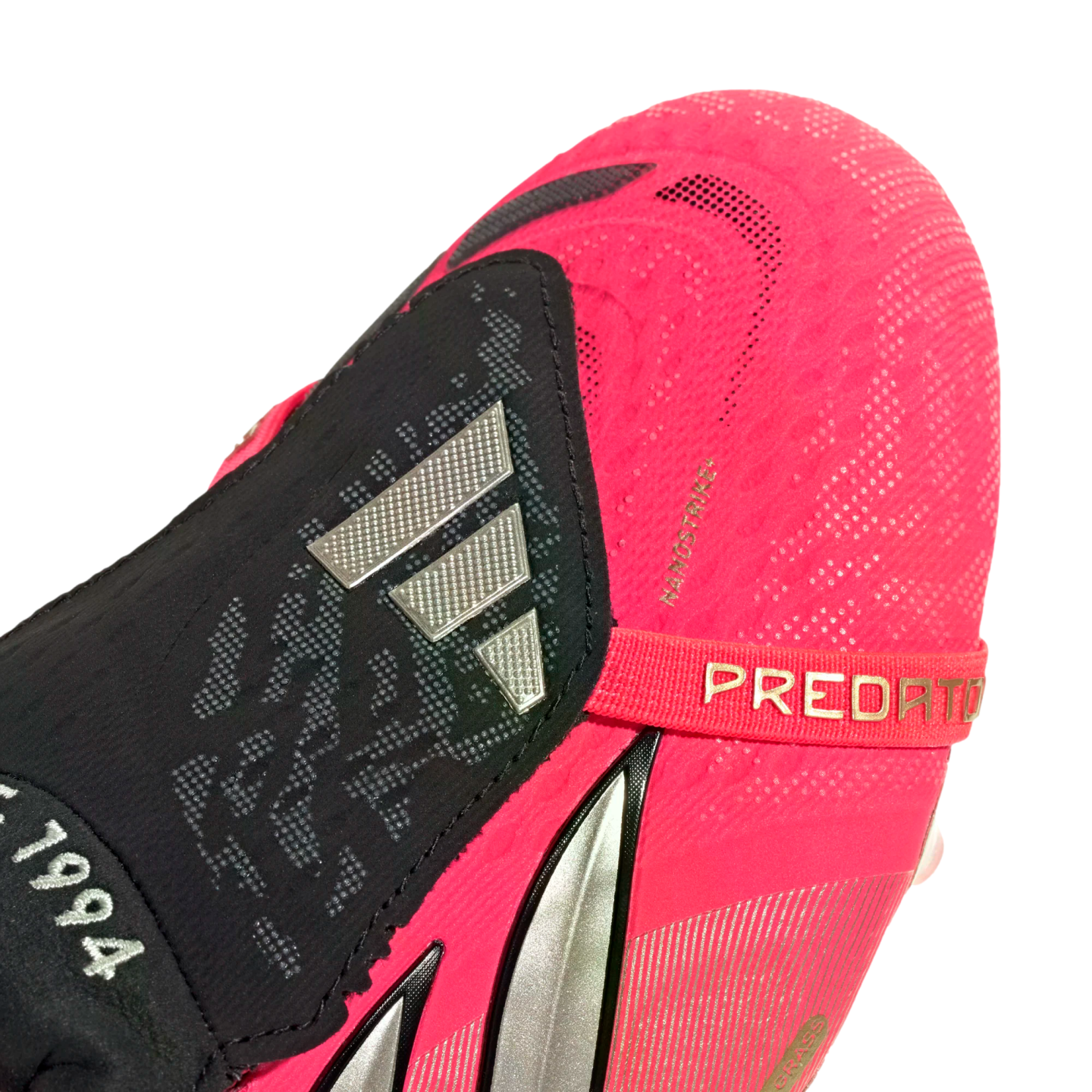 Close-up of a pink Adidas Predator soccer cleat with a black fold-over tongue, silver logo, and pink "PREDATOR" strap.