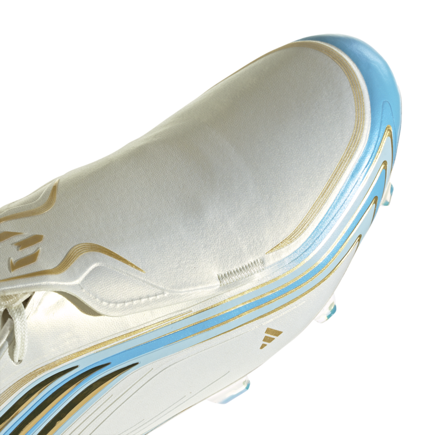 Close-up of a pearlescent silver soccer cleat featuring light blue and gold graphic accents and a gold Adidas logo on the side.