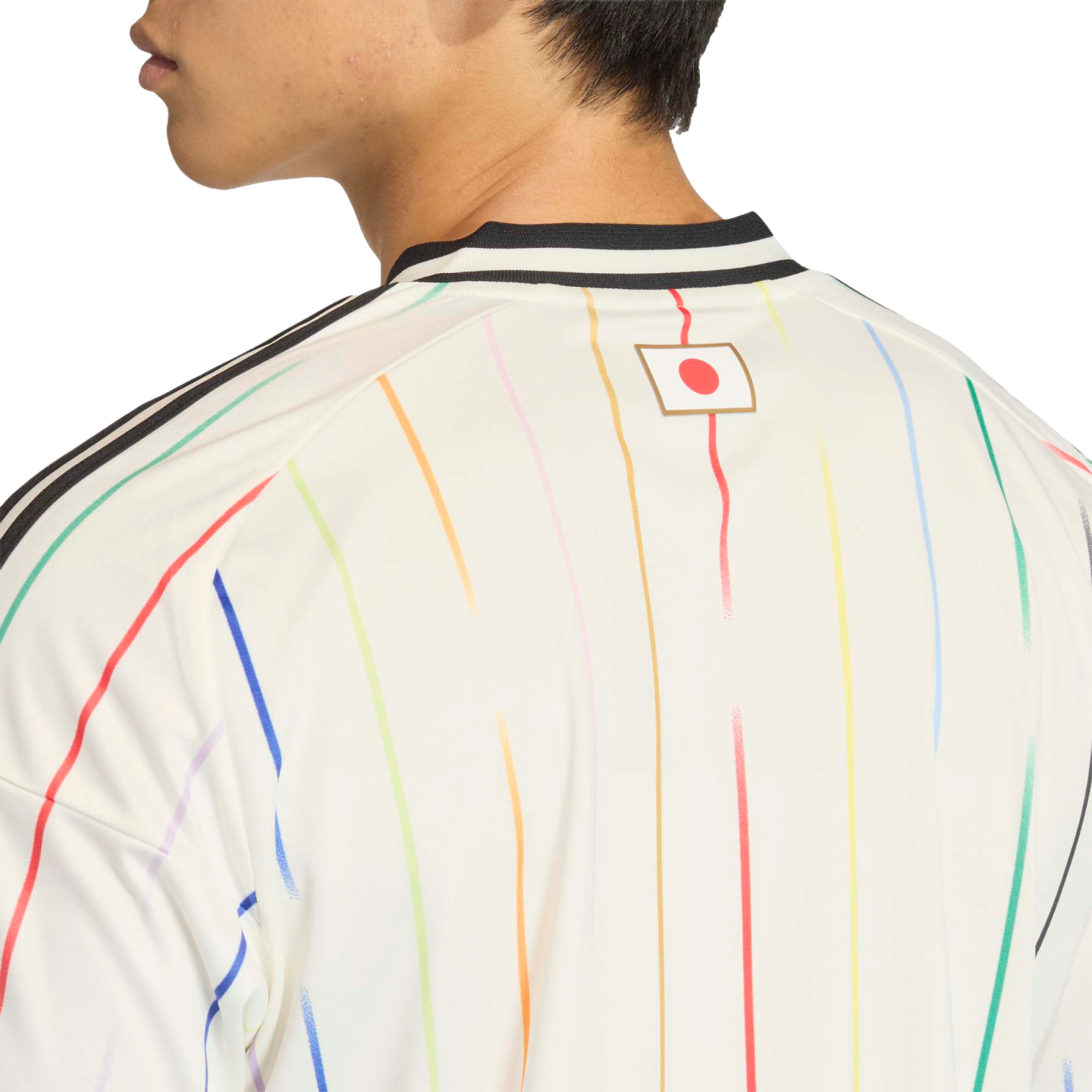 Upper back of a person wearing a white jersey with colorful vertical stripes and a small Japanese flag below the black-and-white striped collar.