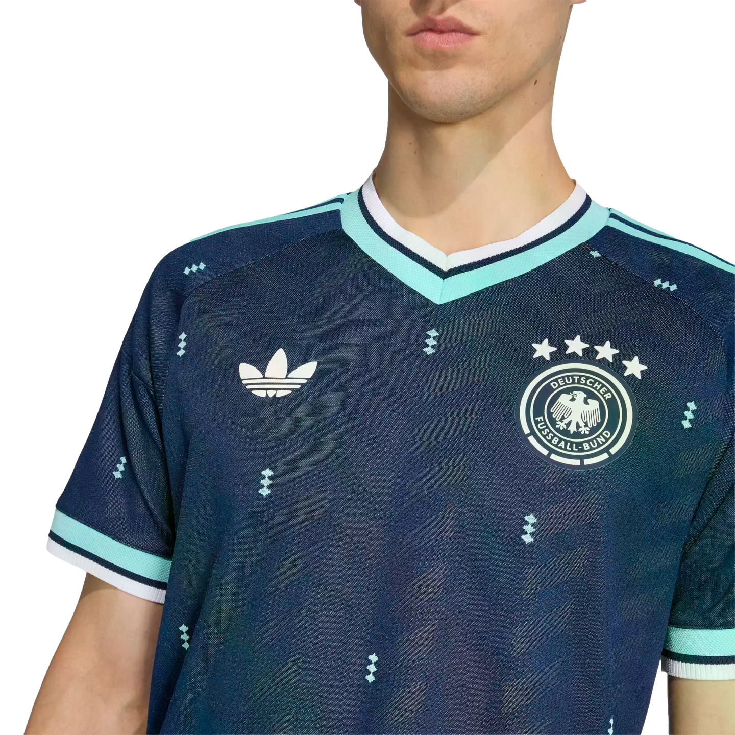 Man wearing a navy blue German soccer jersey with an Adidas trefoil logo, national team crest, and teal trim on the collar and sleeves.