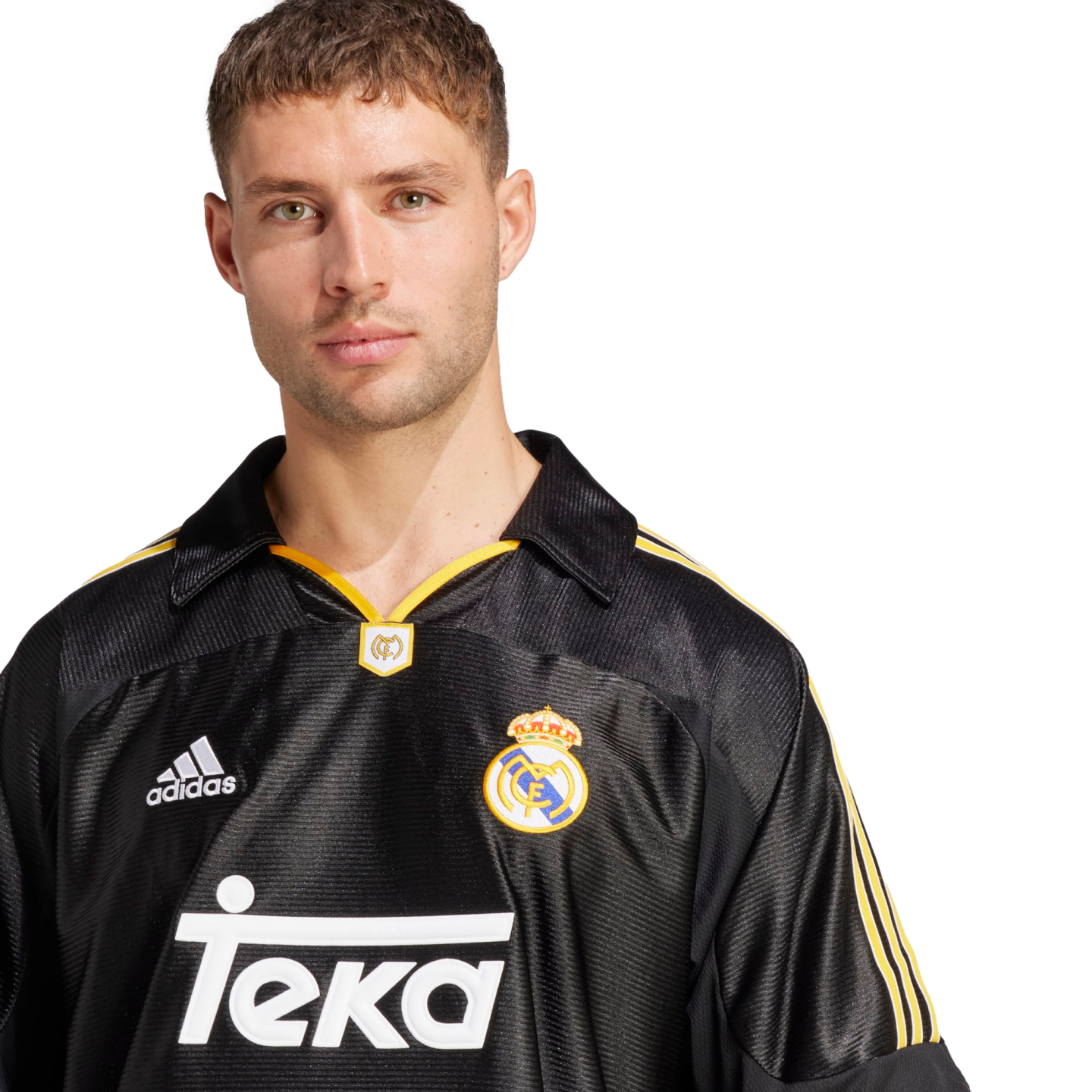 A portrait of a man with light green eyes and short brown hair, wearing a vintage-style black Real Madrid away jersey with yellow accents. The jersey features the adidas logo, the club crest, and the "Teka" sponsor name in white. He is looking directly at the camera against a solid black background.
