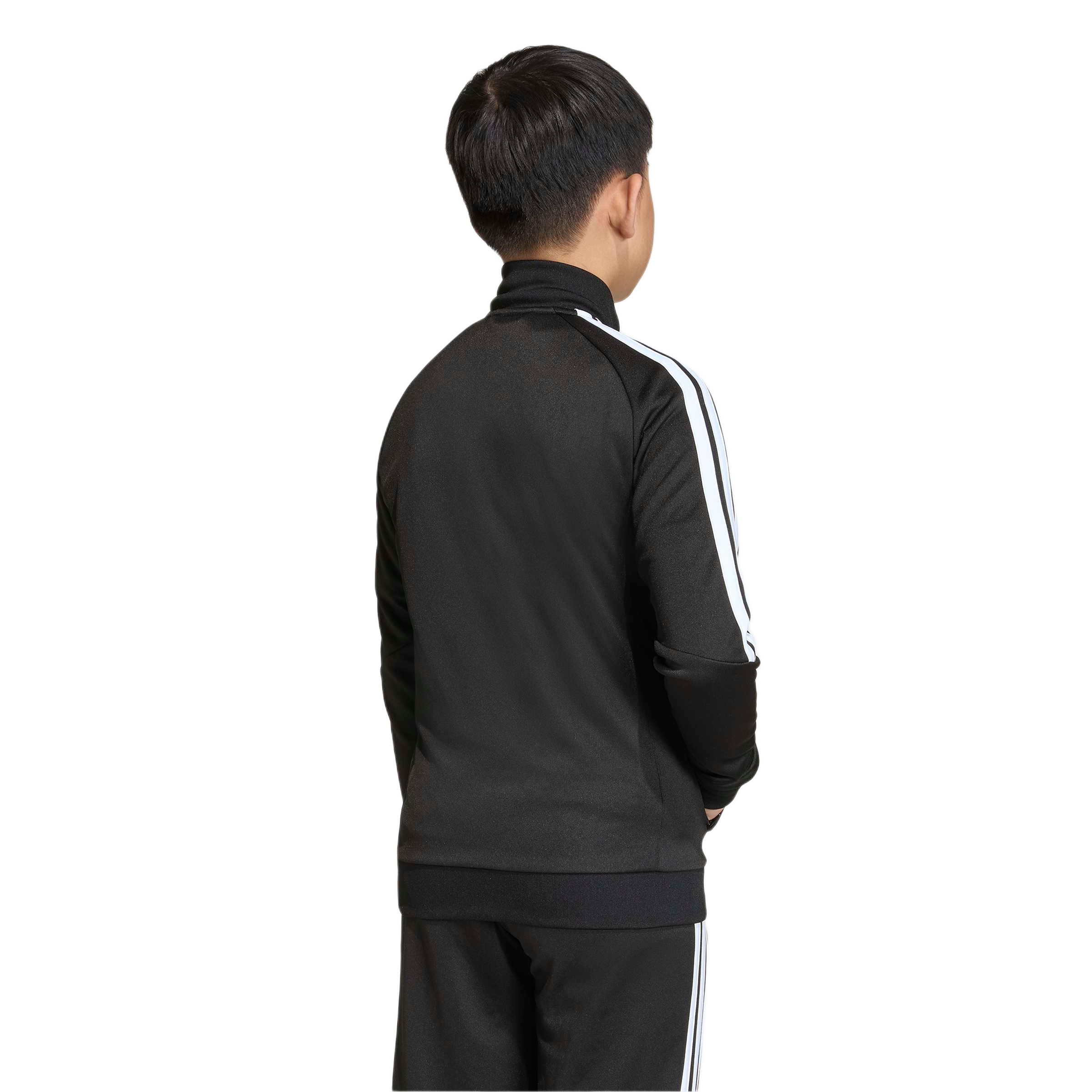 Rear view of a boy wearing a black tracksuit with white stripes, standing against a plain light gray background.