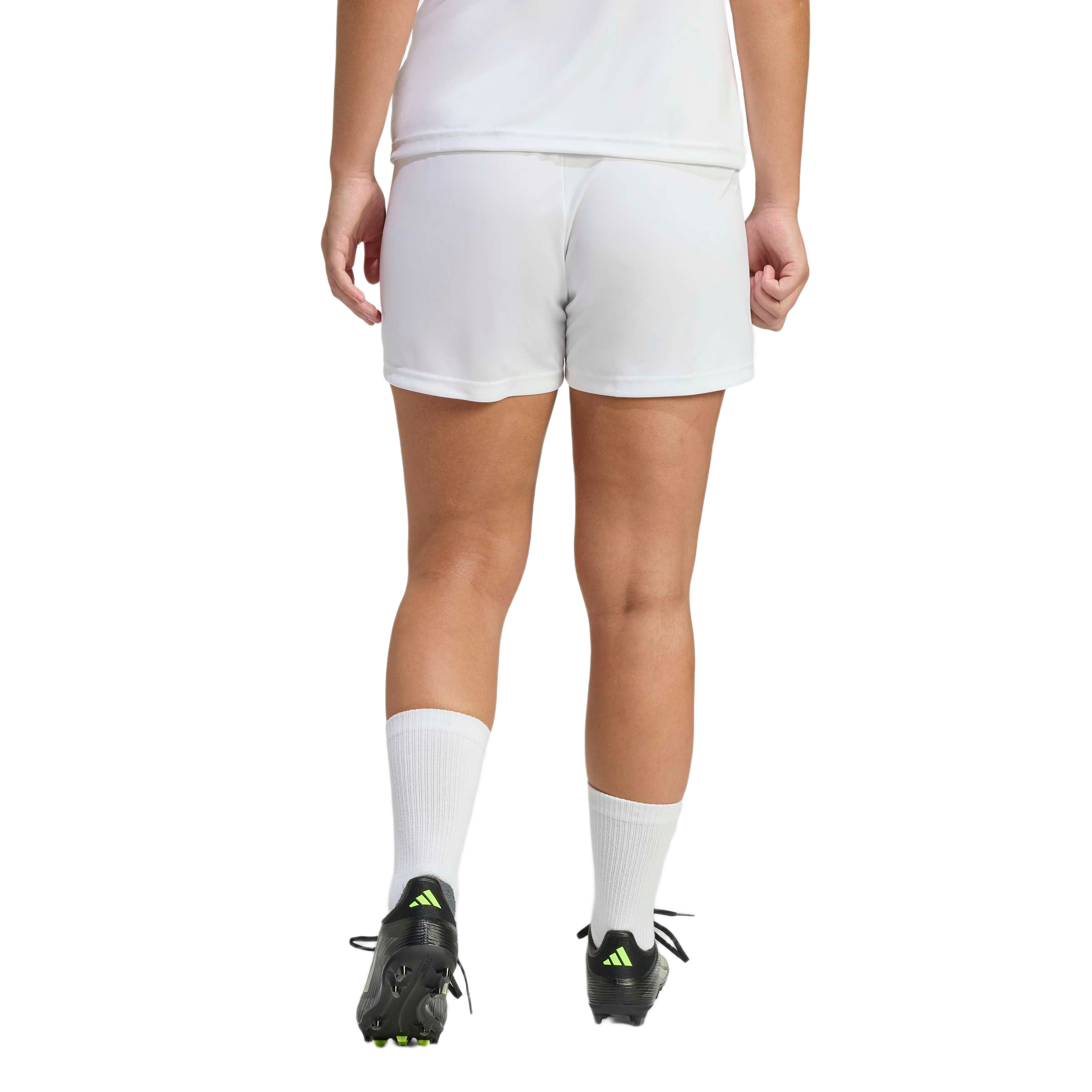 Rear view of a person wearing white athletic shorts, white crew socks, and black soccer cleats with a neon green logo.