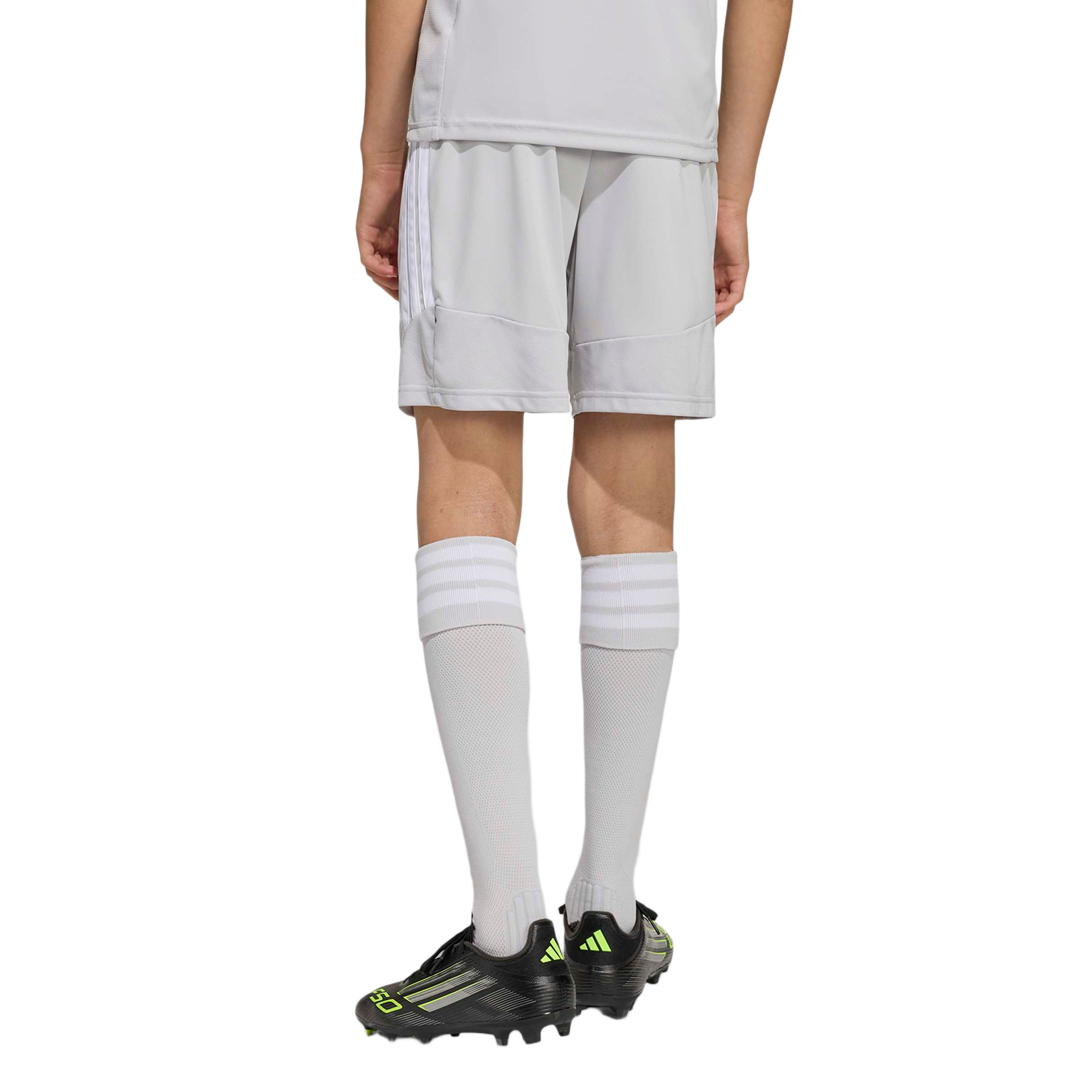 Rear view of a child wearing a light grey Adidas soccer uniform, matching tall socks, and black F50 cleats.