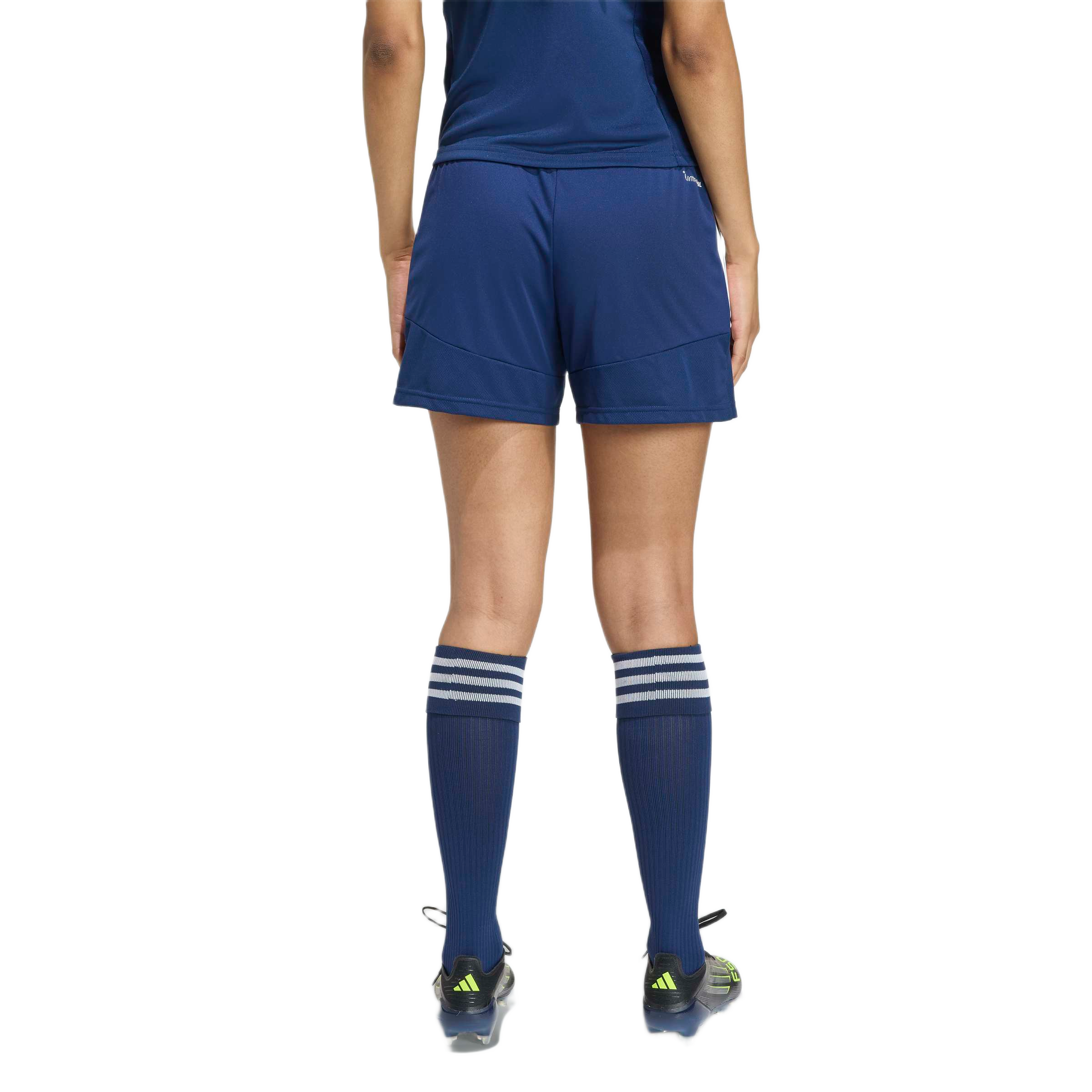 Rear view of an athlete wearing a navy blue soccer uniform, striped knee-high socks, and black cleats.