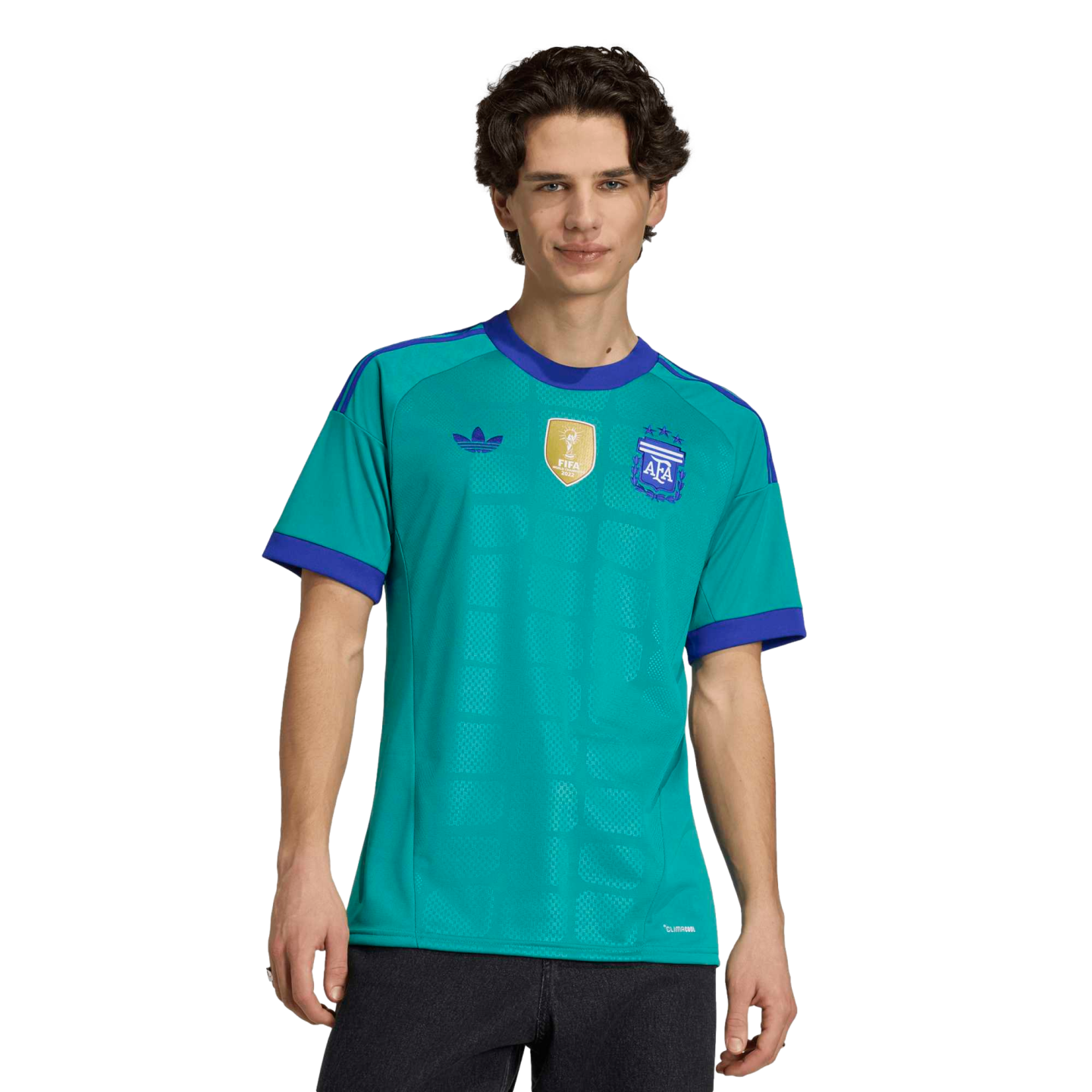 A man wearing a teal Argentina soccer jersey with purple trim, featuring the AFA crest and FIFA World Champions patch, against a black background.