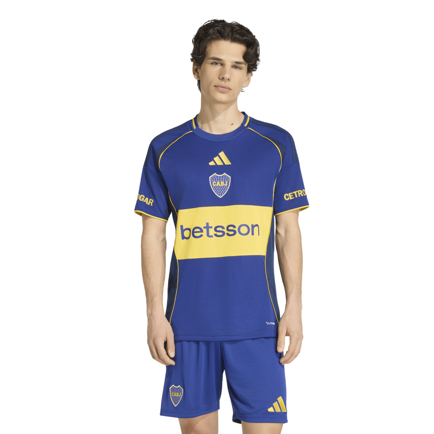 A man models a blue and yellow Boca Juniors soccer kit featuring the 'betsson' sponsor logo and club crest against a white background.