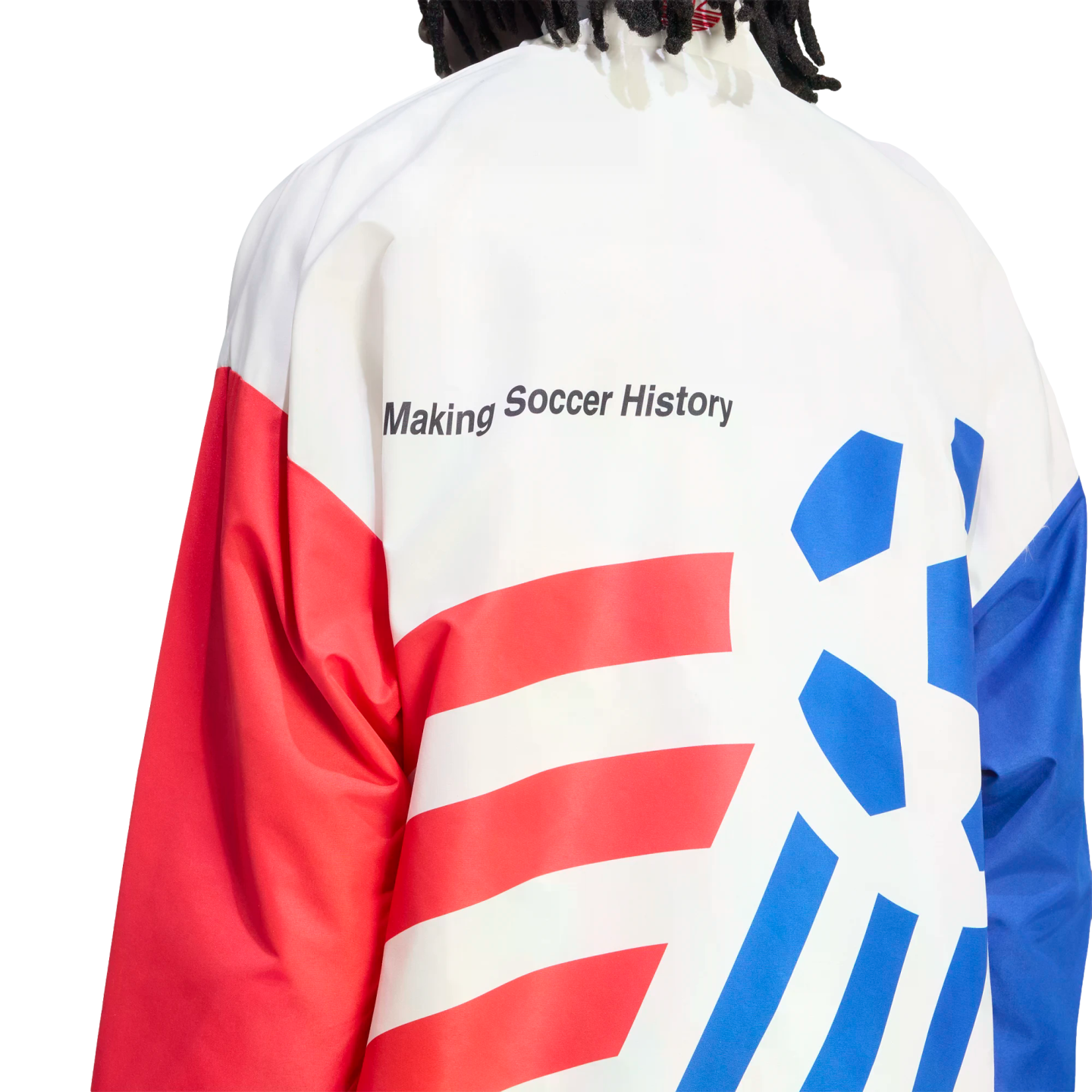 A close-up view from behind of a person wearing a white, red, and blue athletic jacket against a black background. The text "Making Soccer History" is printed in black on the white upper back. The lower back features red horizontal stripes on the left and blue diagonal stripes and a soccer ball graphic on the right.