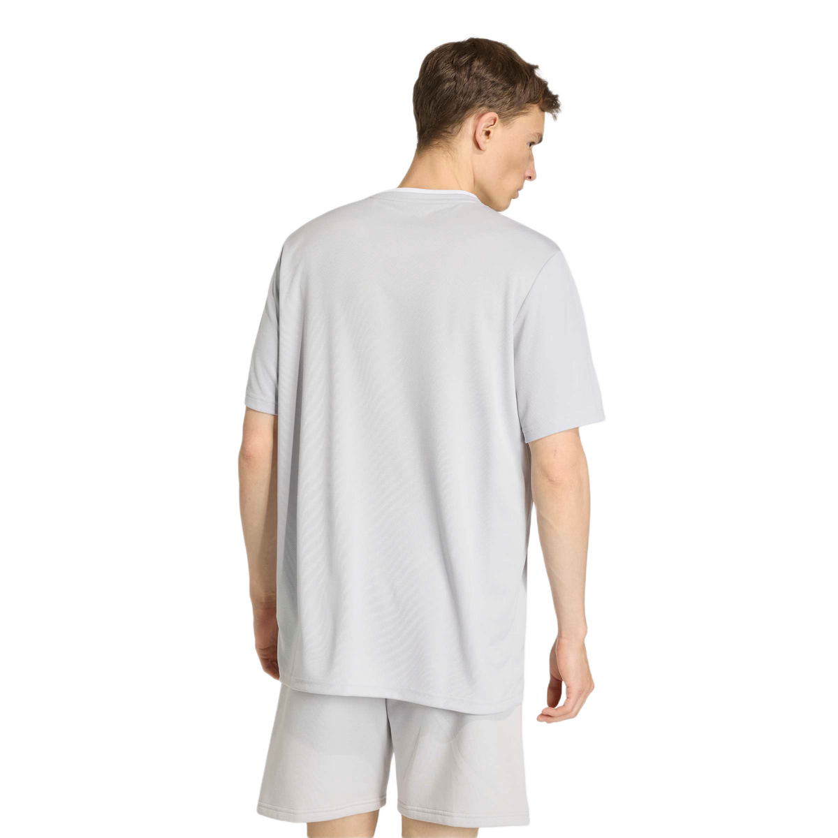 Back view of a man wearing a light grey short-sleeved t-shirt and matching shorts.