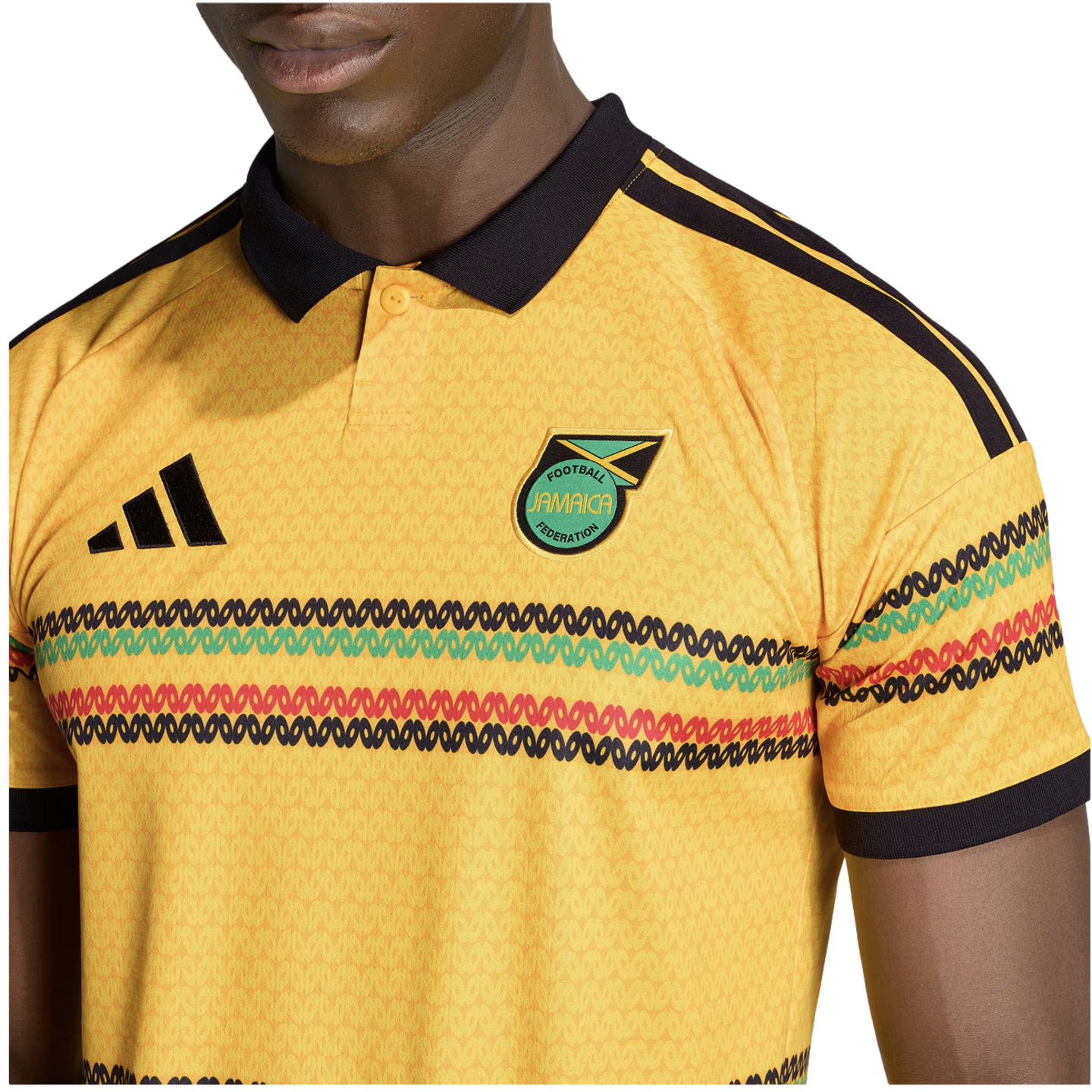 Close-up of a person wearing a yellow Adidas Jamaica national football team jersey with a black collar and colorful horizontal patterns.