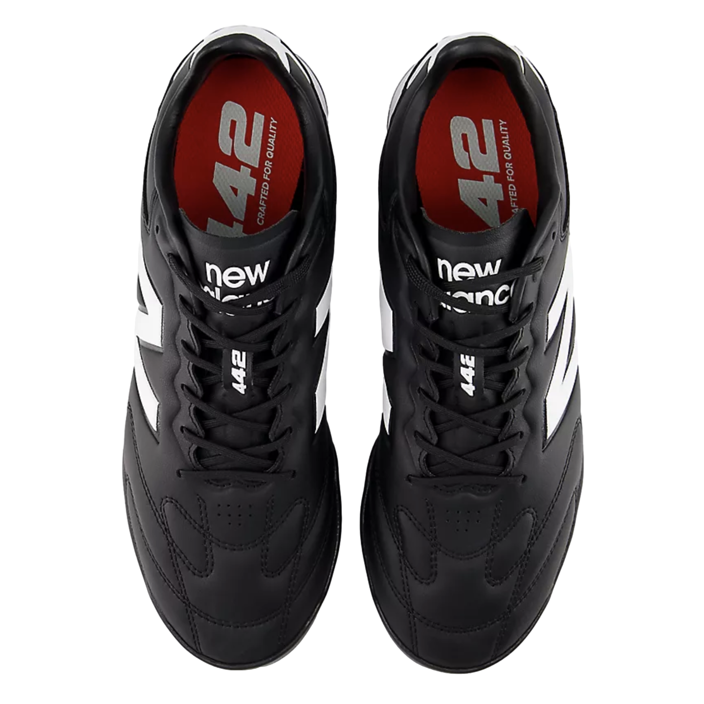 Top-down view of black New Balance 442 soccer cleats with white accents and red insoles on a black background.