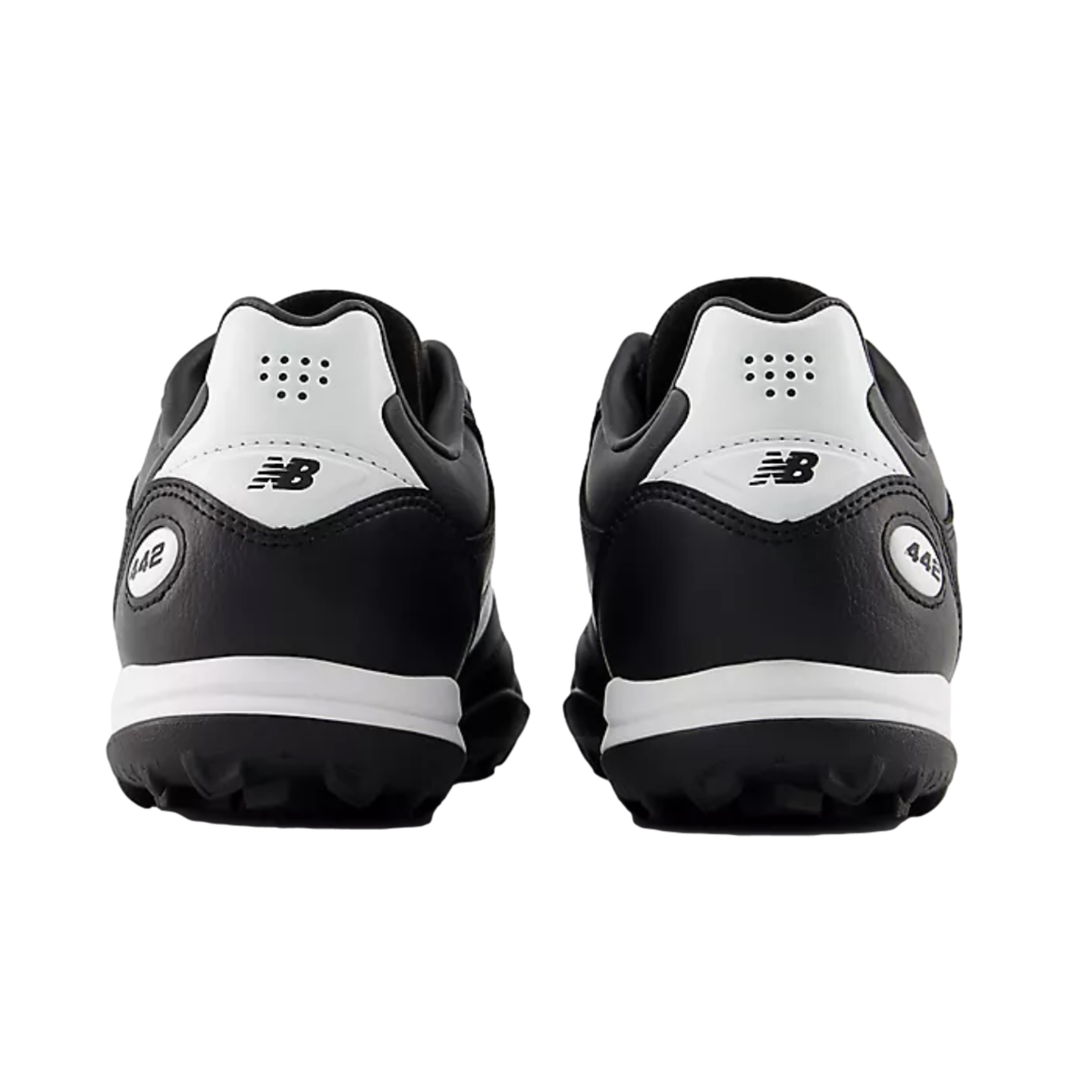 Rear view of a pair of black and white New Balance 442 turf soccer shoes against a solid black background.