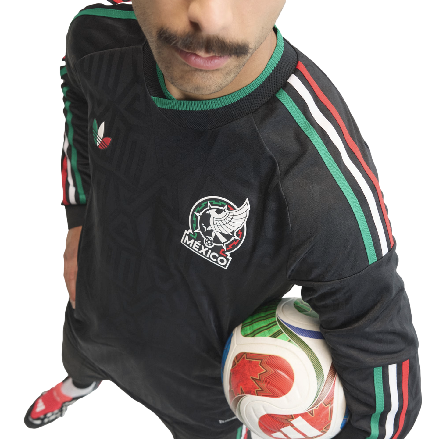 High-angle shot of a man with a mustache wearing a black Mexico soccer jersey and holding a soccer ball against a white background.
