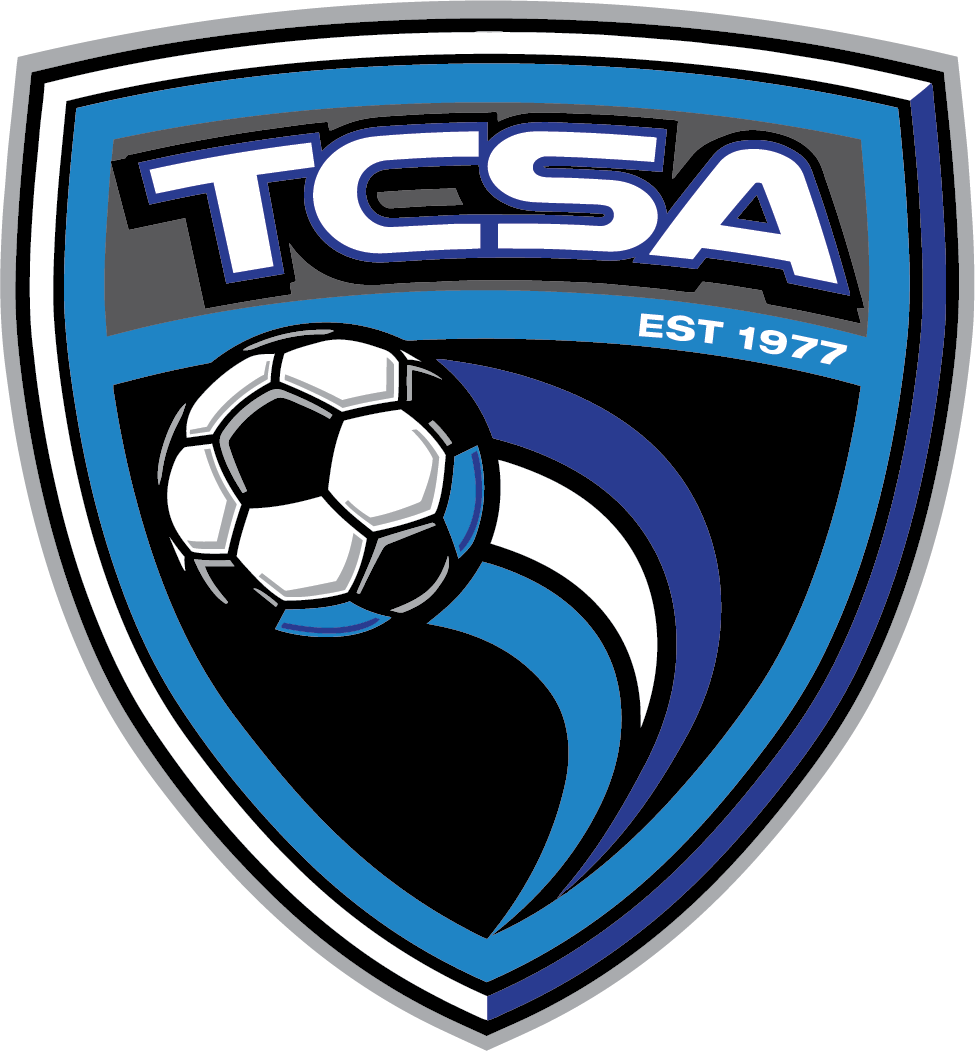 Shield-shaped TCSA soccer logo featuring a soccer ball with motion trails, the letters "TCSA", and "EST 1977" in blue, black, and white.