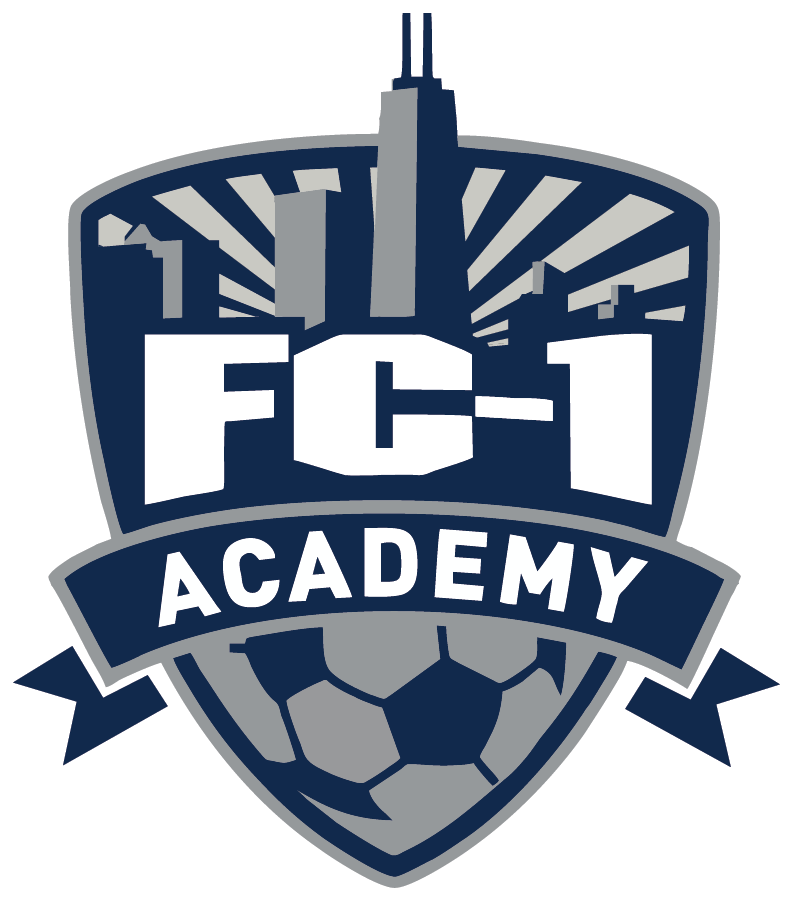 A navy blue and grey shield-shaped logo for FC-1 Academy featuring a stylized Chicago skyline against a sunburst background at the top, large white letters reading "FC-1" in the center, and a grey soccer ball at the bottom. A navy blue banner with the word "ACADEMY" in white spans across the middle.