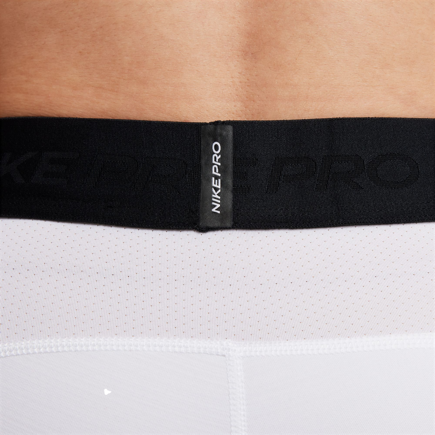 Close-up of a black Nike Pro elastic waistband on white mesh performance shorts.