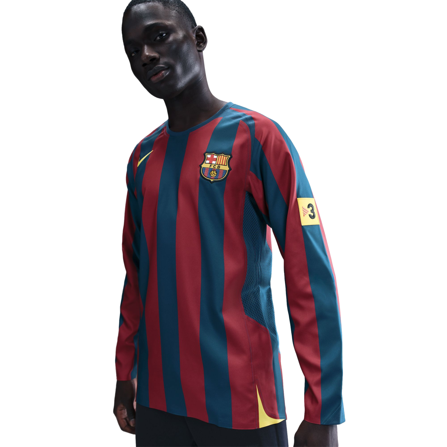 A man wearing a long-sleeved FC Barcelona soccer jersey with vertical maroon and blue stripes. The jersey features the club crest on the chest, a yellow Nike logo, and a yellow patch with the number 3 on the left sleeve. The background is solid black.