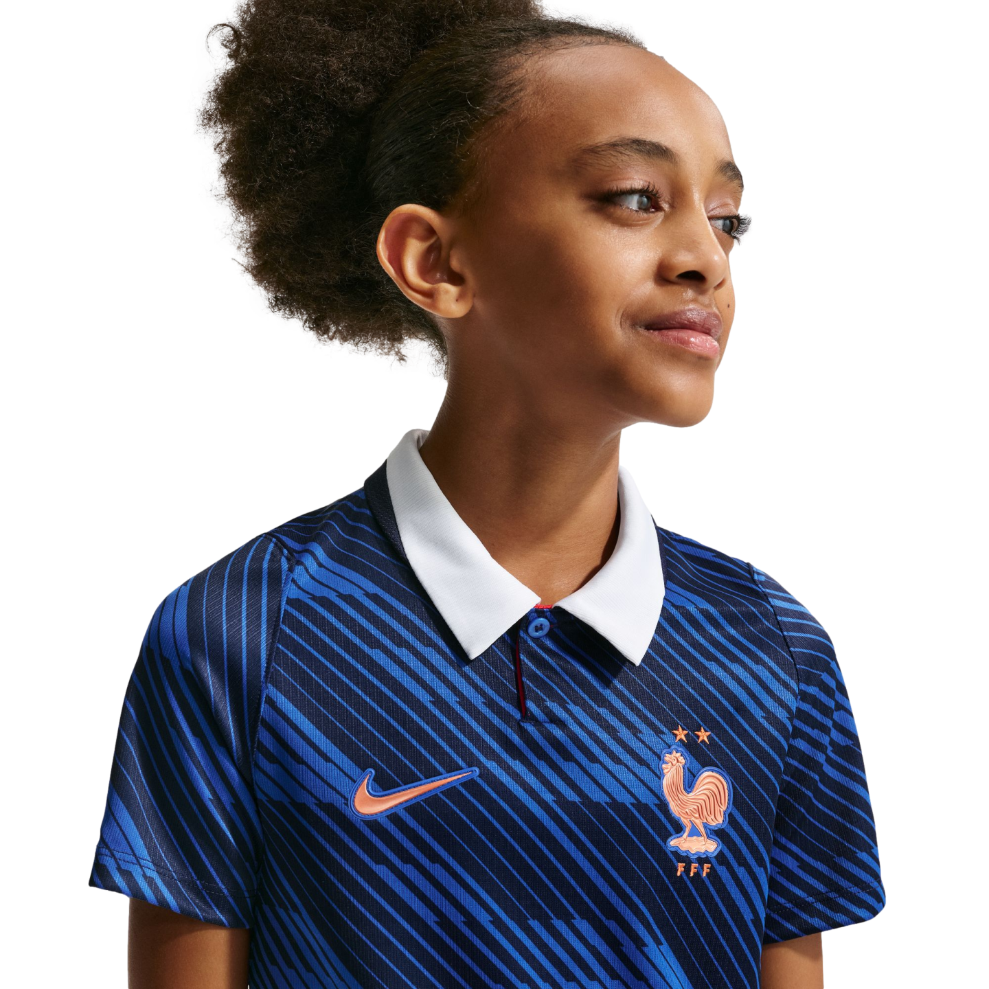 A young girl in a blue patterned France national team soccer jersey with a white collar, looking off-camera against a black background.