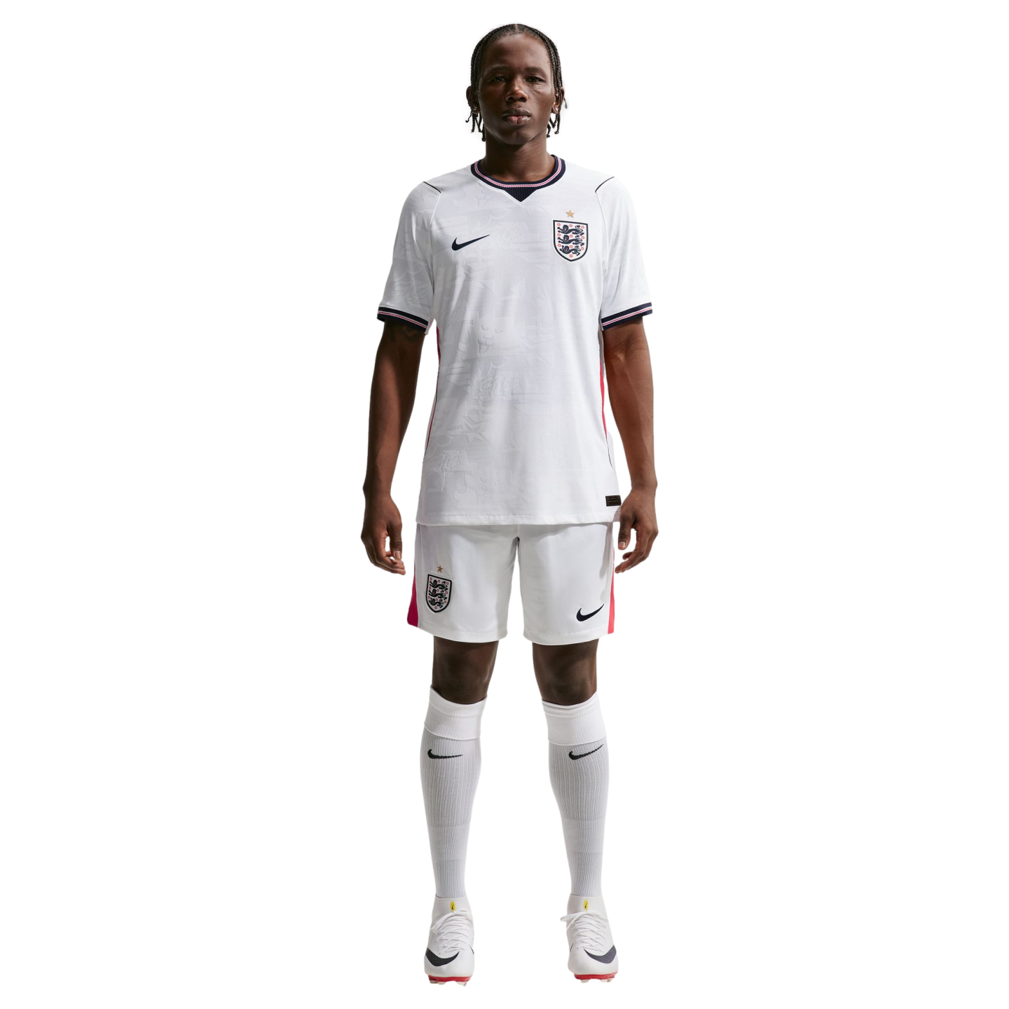 A full-body photograph of a male athlete standing against a solid black background, wearing the white Nike England national team home soccer kit. The kit includes a white jersey and shorts featuring the team's Three Lions crest and Nike logo, paired with matching white knee-high socks and white cleats.