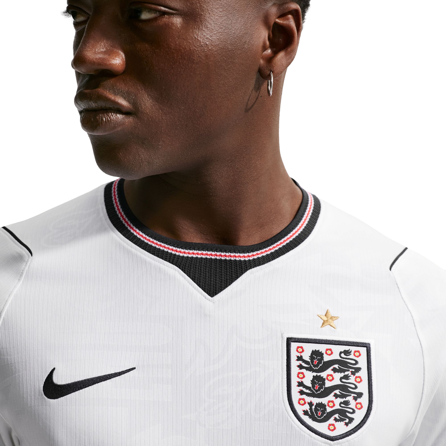 Close-up of a man in a white England national football team jersey with the Three Lions crest and Nike logo against a black background.