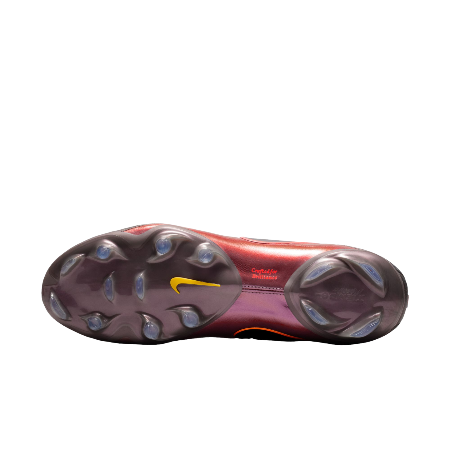 Bottom view of an iridescent maroon Nike soccer cleat soleplate with clear studs, a yellow swoosh, and "Crafted for Brilliance" text, set against a solid black background.