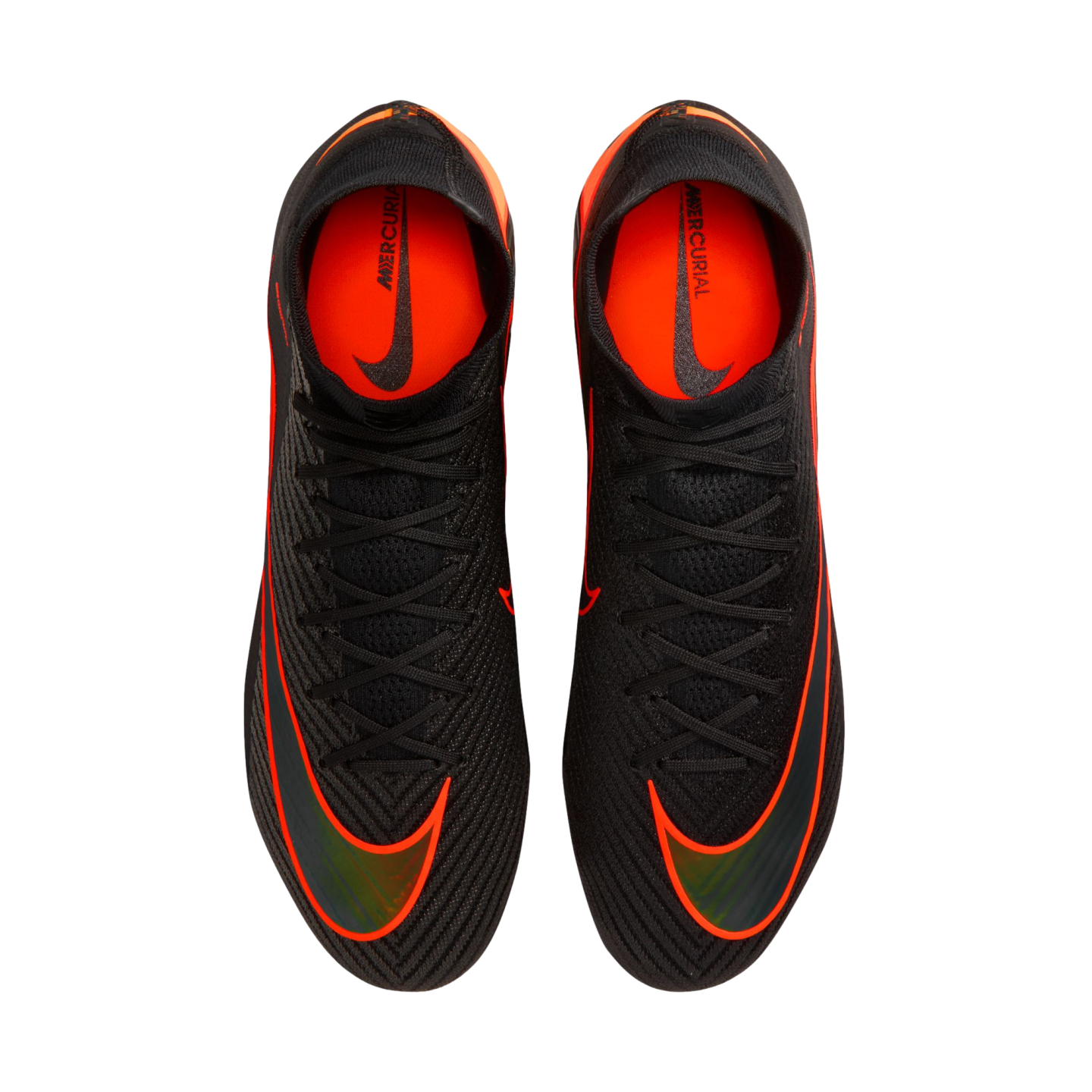 An overhead view of a pair of black Nike Mercurial soccer cleats with vibrant orange accents and black laces, set against a solid black background. The shoes feature large orange swooshes on the forefoot and bright orange interior linings with "MERCURIAL" branding.