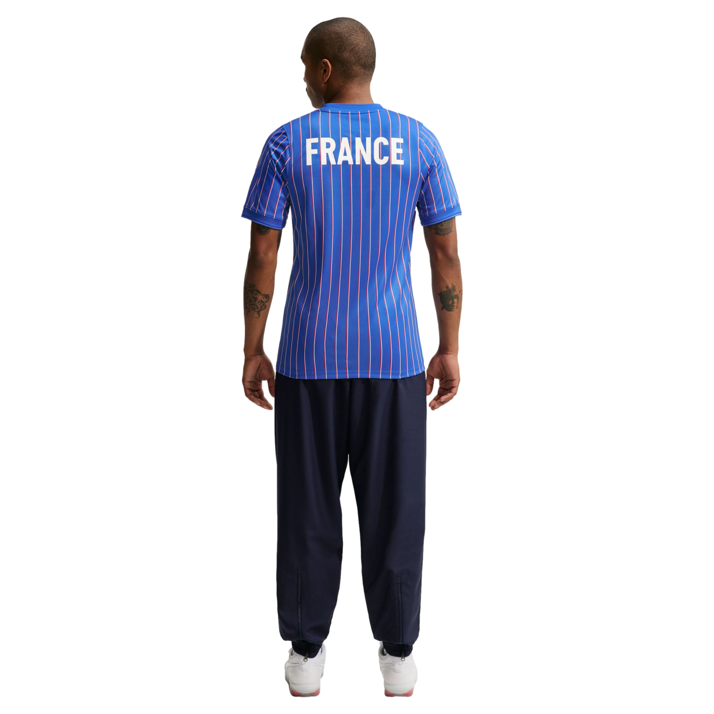 Back view of a person wearing a blue pinstriped "FRANCE" jersey, navy blue joggers, and white sneakers against a white background.