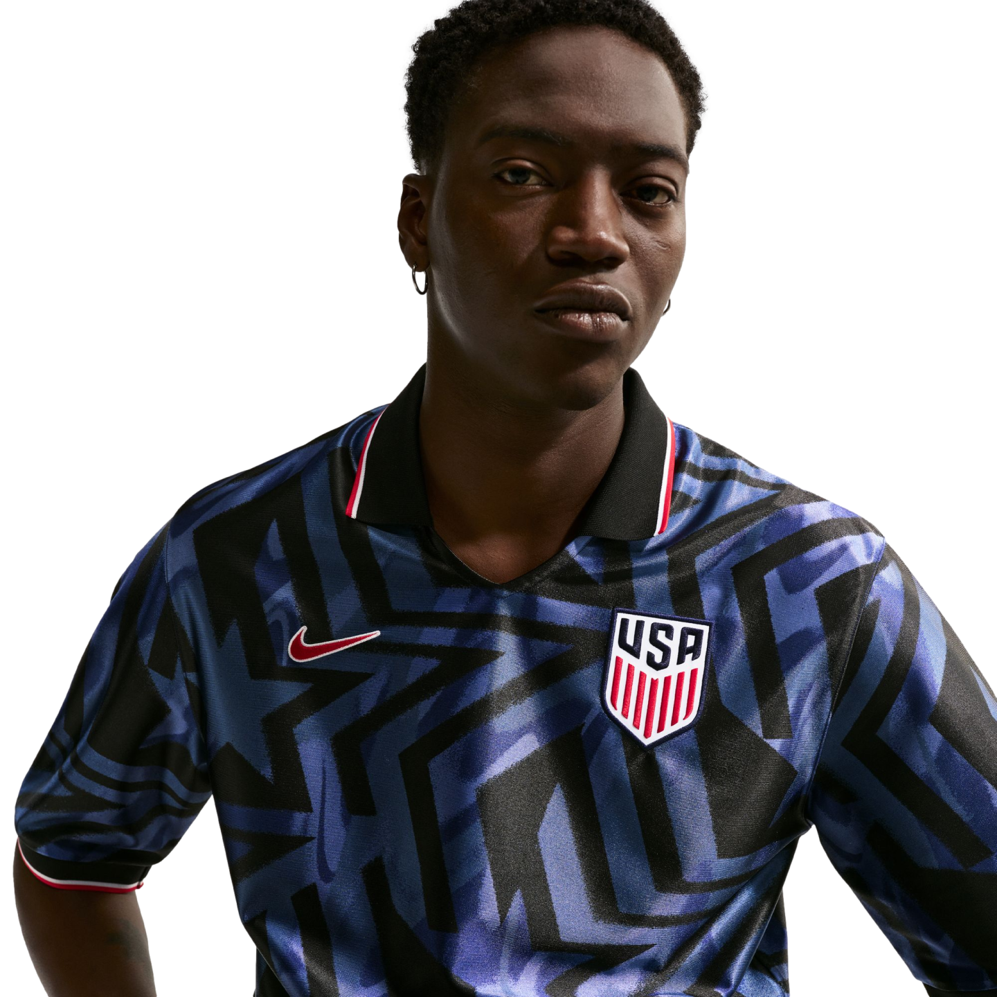 A man wearing a blue and black geometric pattern Nike USA soccer jersey with a USA crest, against a plain white background.