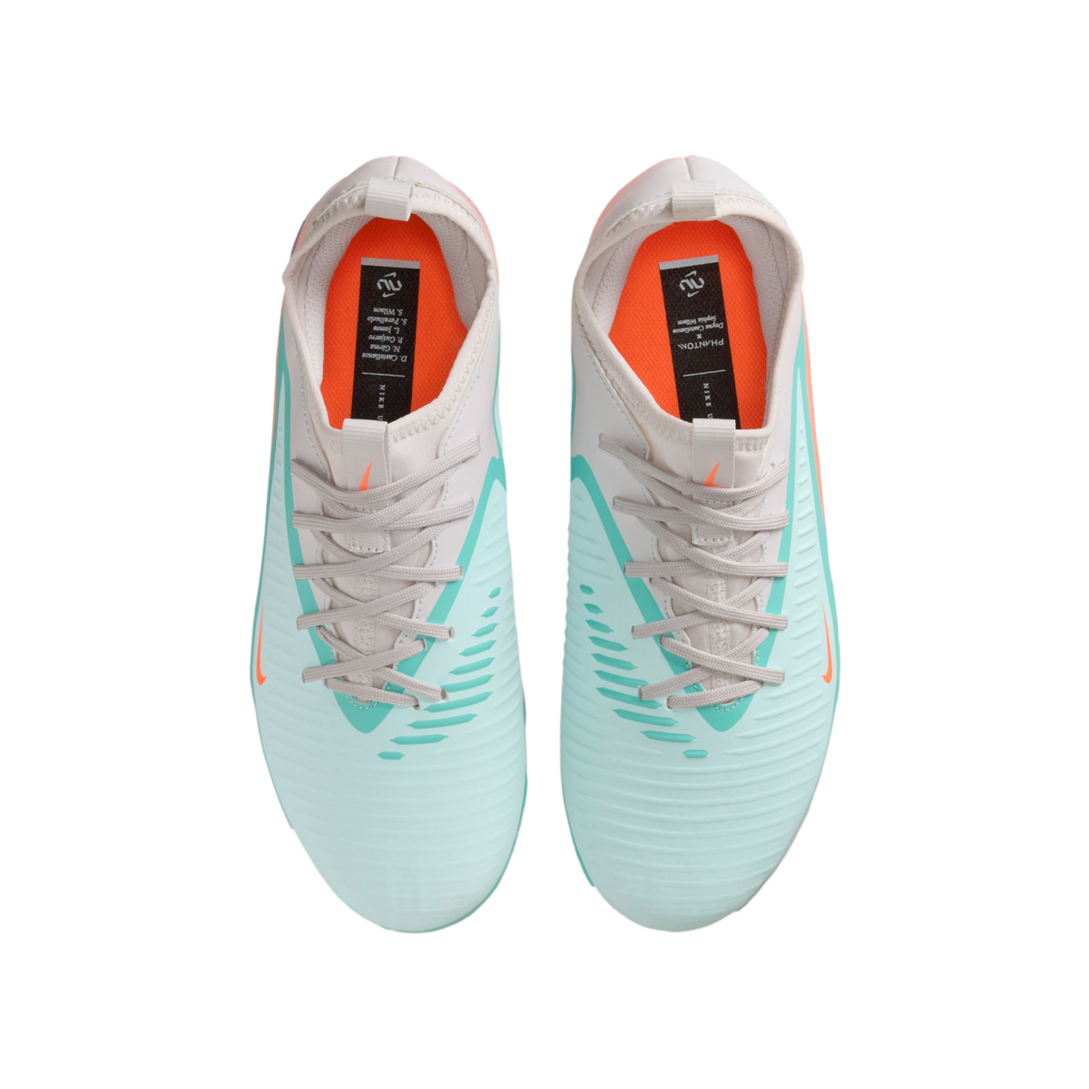 Top-down view of Nike soccer cleats in mint green and light grey with bright orange insoles and accents, set against a solid black background.