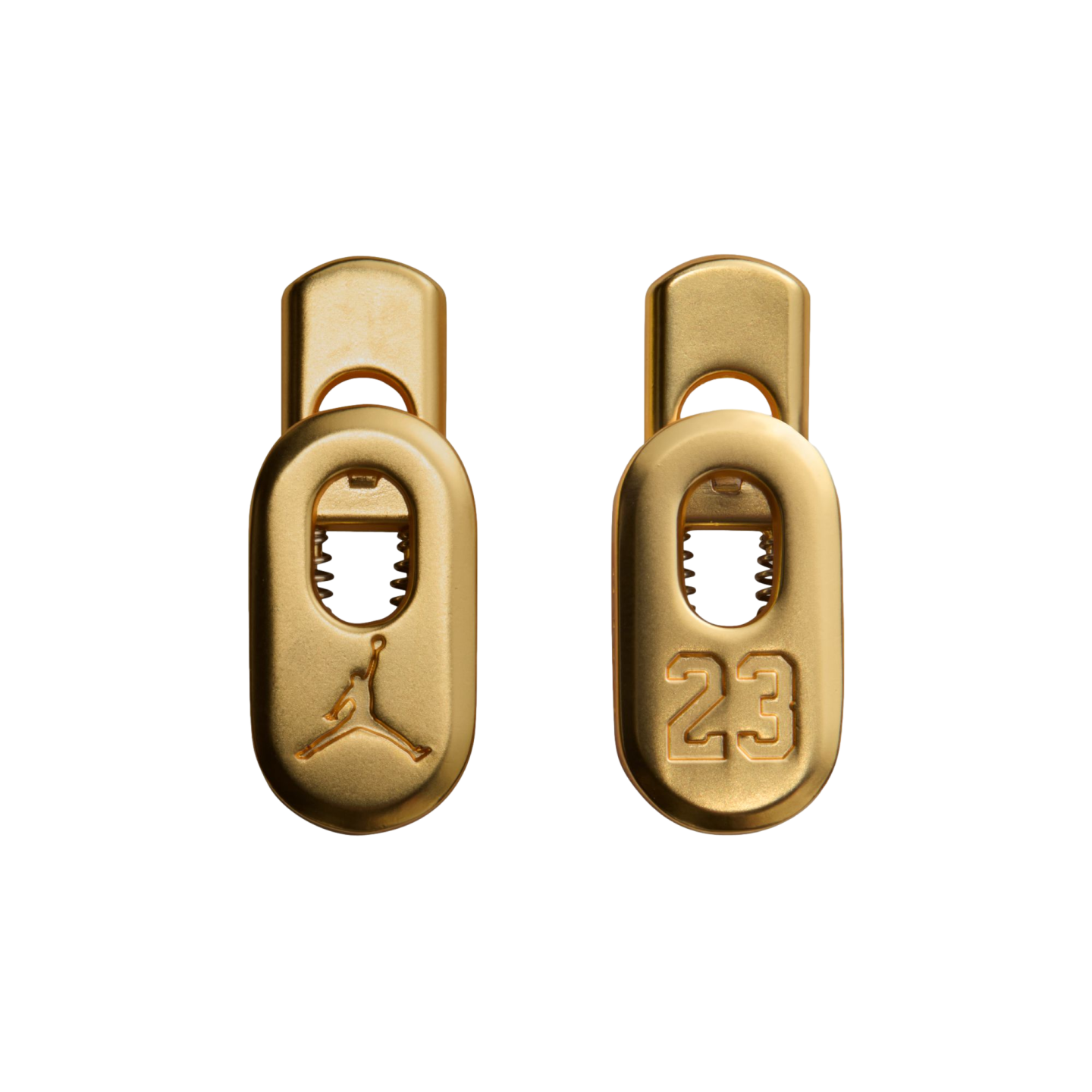 Two gold-colored metal lace toggles featuring a debossed Jumpman logo and the number 23, centered against a solid black background.