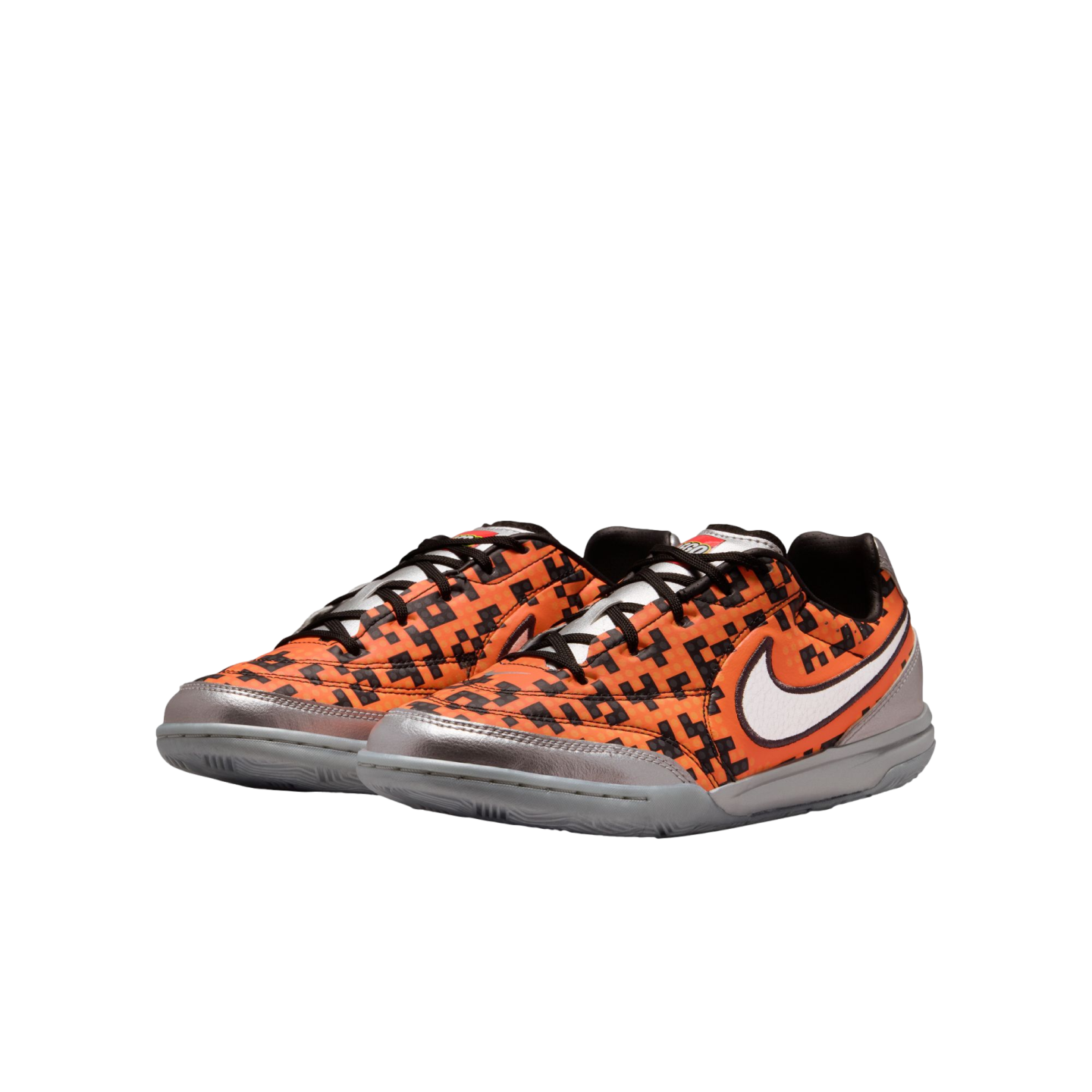 A pair of orange and black pixelated Nike sneakers with silver metallic accents, a white swoosh, and grey soles.