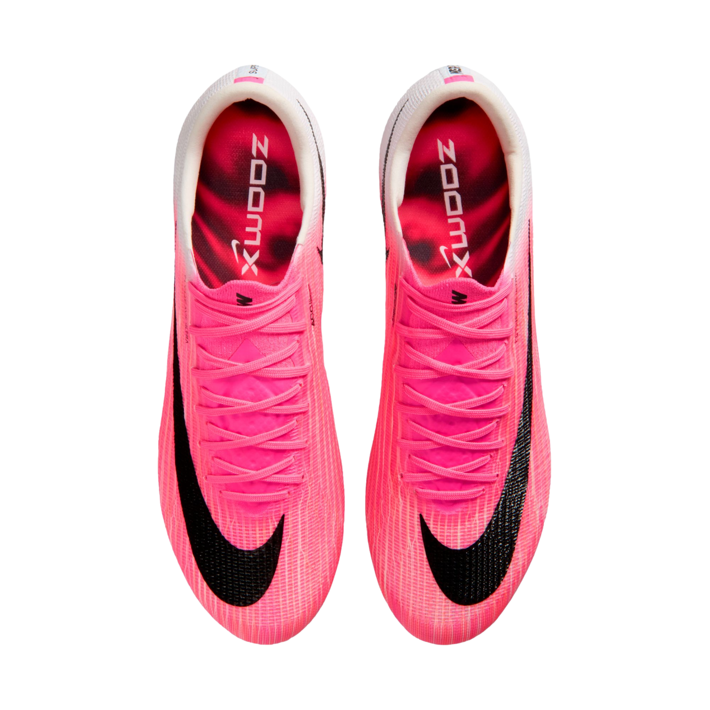 Top-down view of bright pink Nike soccer cleats on a white background. Each shoe features a large black swoosh, pink laces, and "ZOOMX" printed on the inner sole.