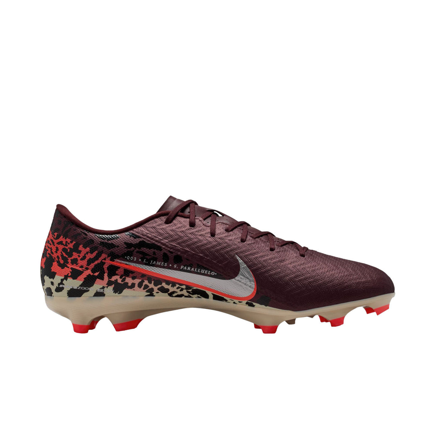 A side profile of a Nike soccer cleat against a solid black background. The shoe features a dark maroon textured upper, a silver Nike swoosh with a red outline, and a tan soleplate with bright red studs. A graphic pattern in red, black, and tan covers the heel area. Narrow white text above the swoosh reads "003 x L. JAMES + S. PARALLUELO."