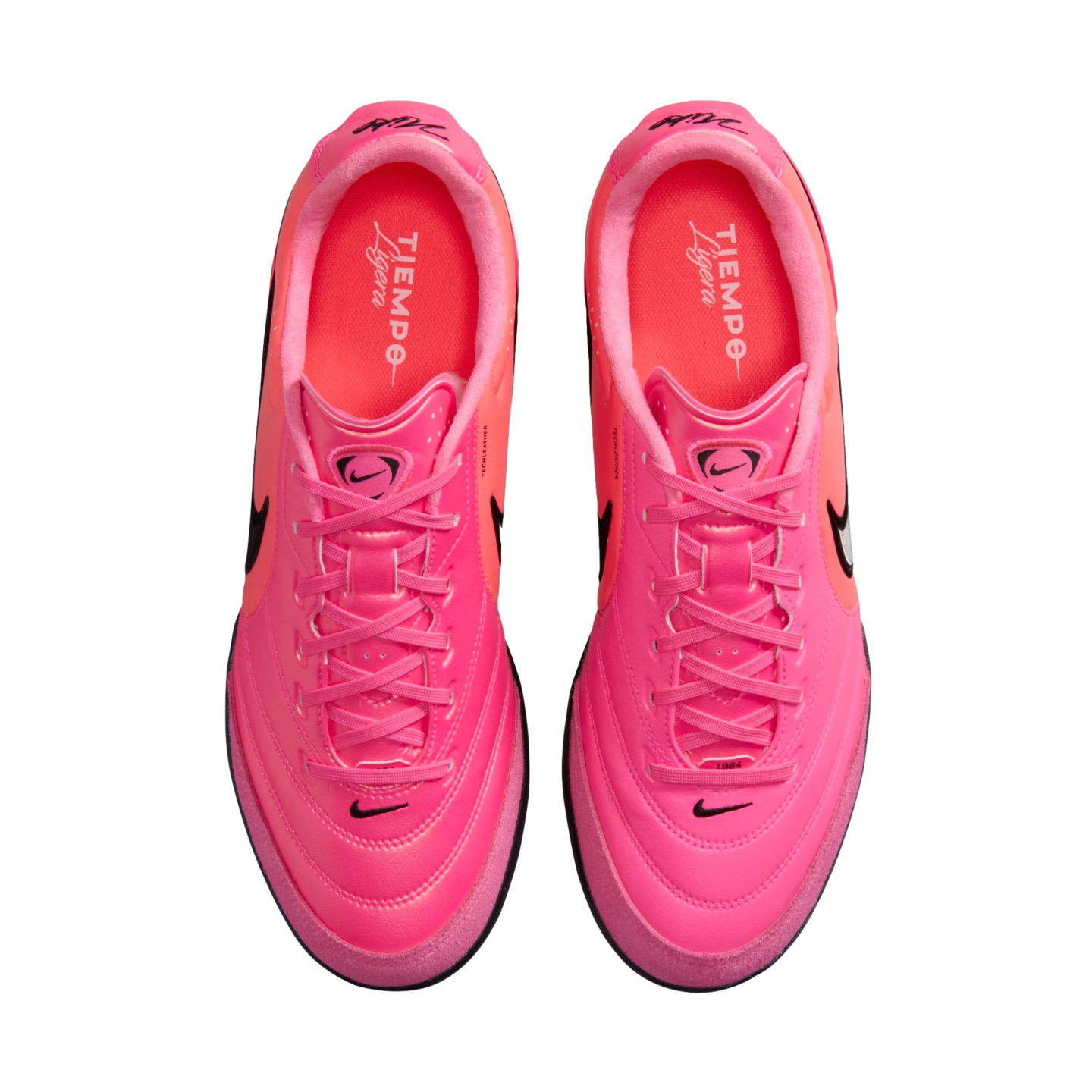 Top-down view of a pair of bright pink Nike Tiempo Ligera soccer shoes on a white background.