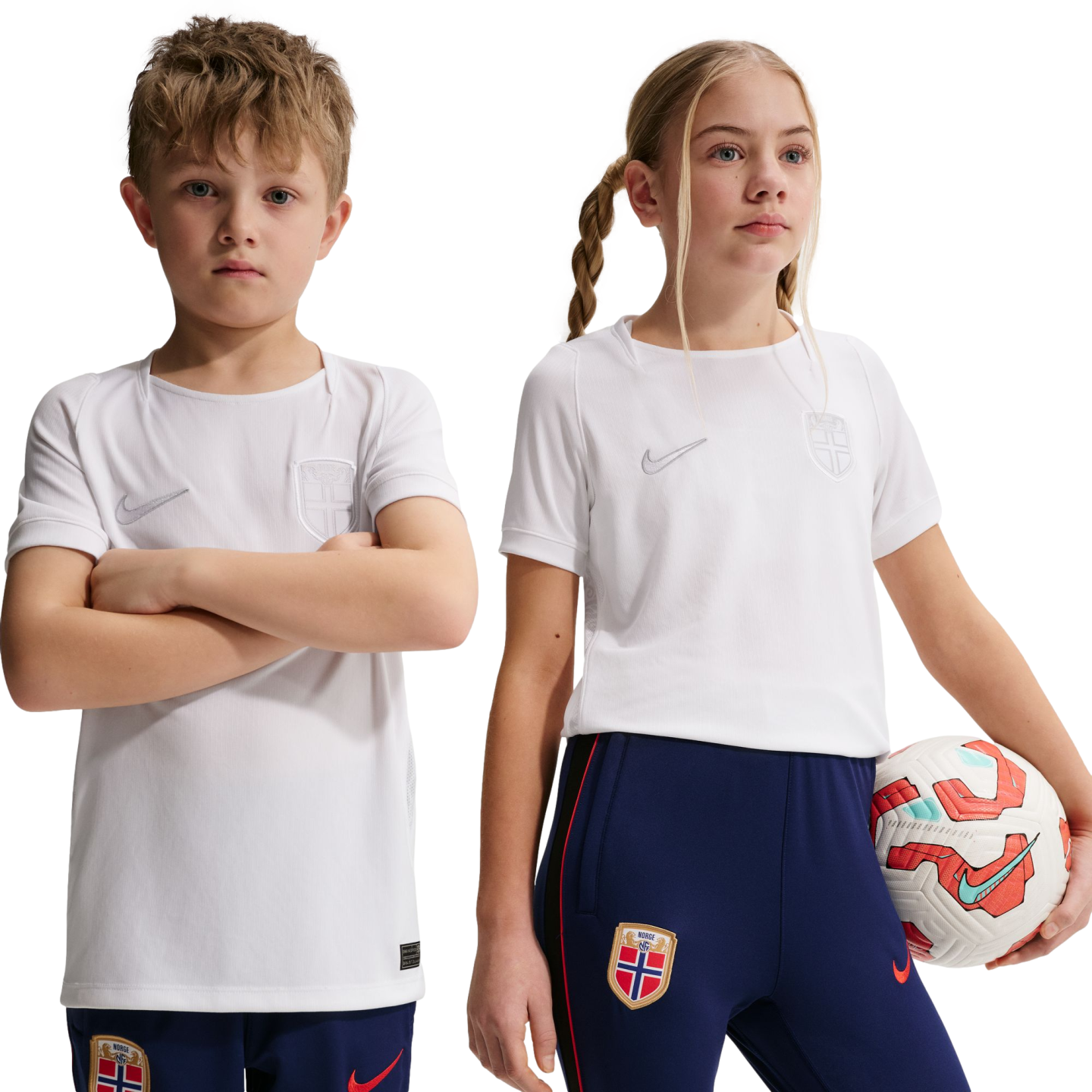 Two children in white Nike soccer jerseys and blue pants with Norway national team crests. The girl holds a soccer ball against a black background.